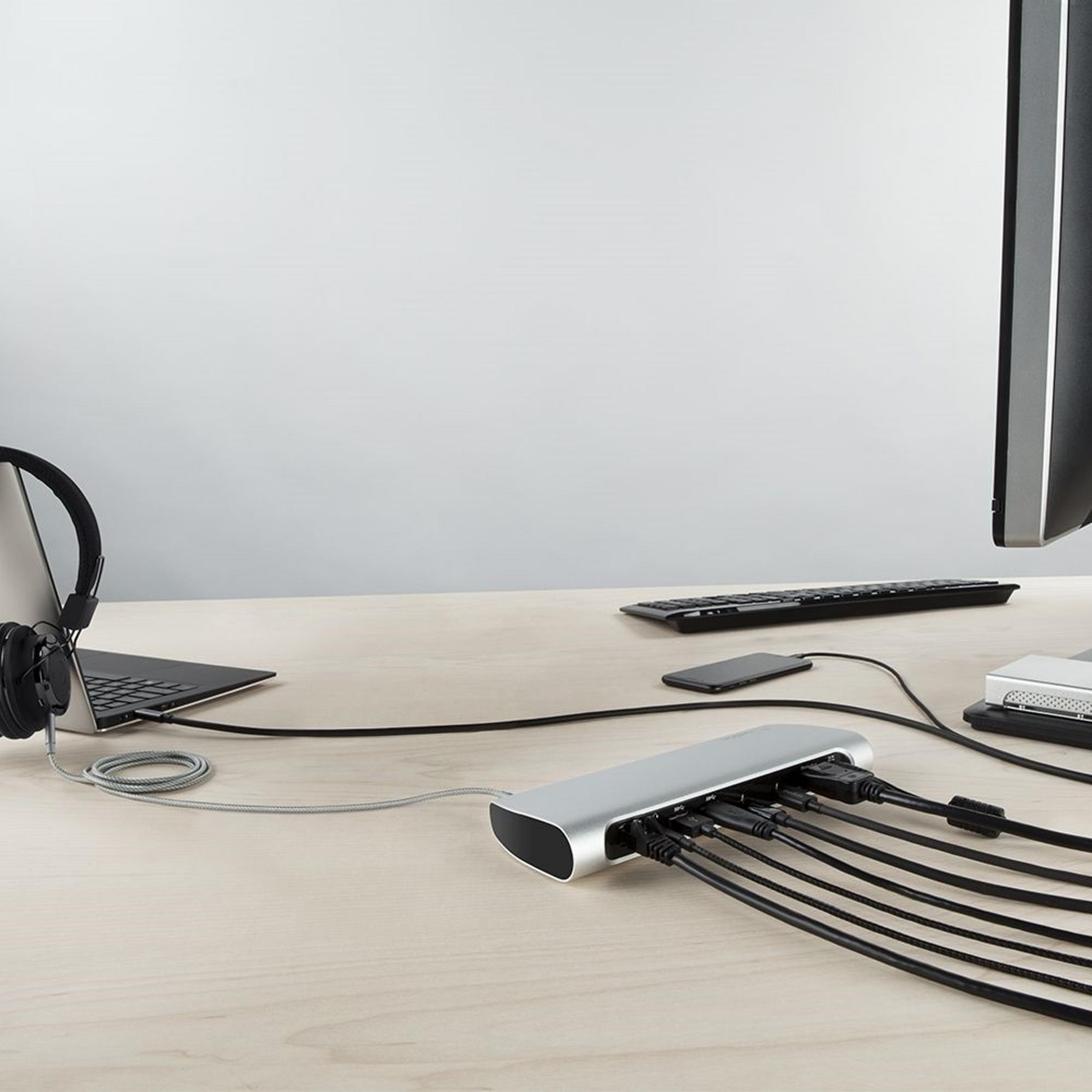 Ein Schreibtisch mit Laptop, Kopfhörern, Tastatur, Handy und einem USB-Hub.