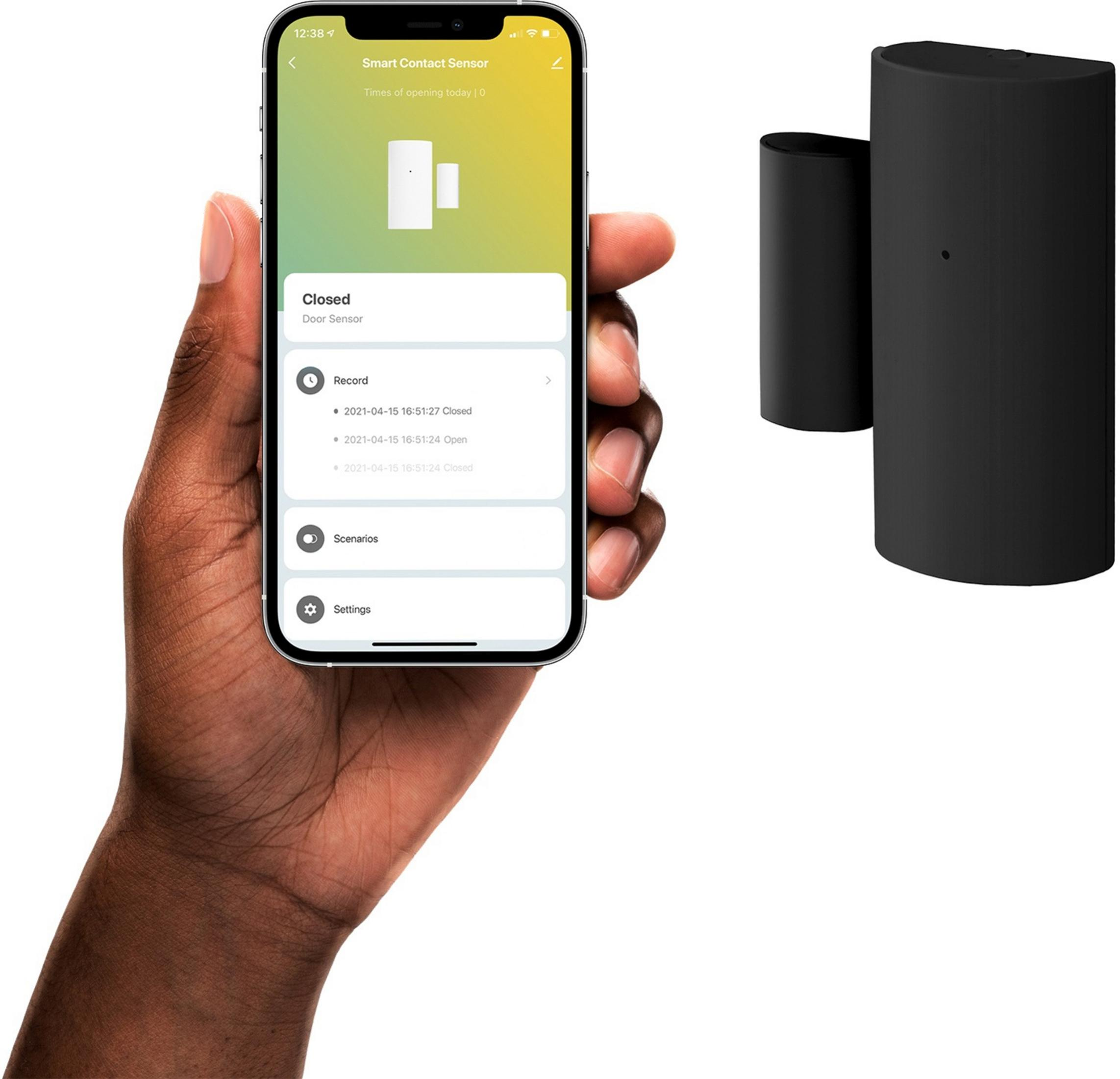 Eine Hand hält ein Smartphone mit einer Türsensoren-App. Daneben ein schwarzer Türkontaktsensor.