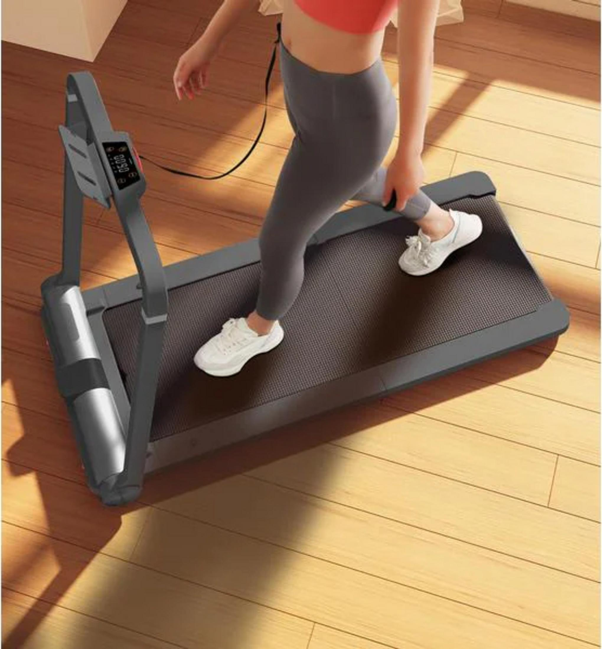 Kobieta w stroju sportowym ćwiczy na bieżni w pokoju.