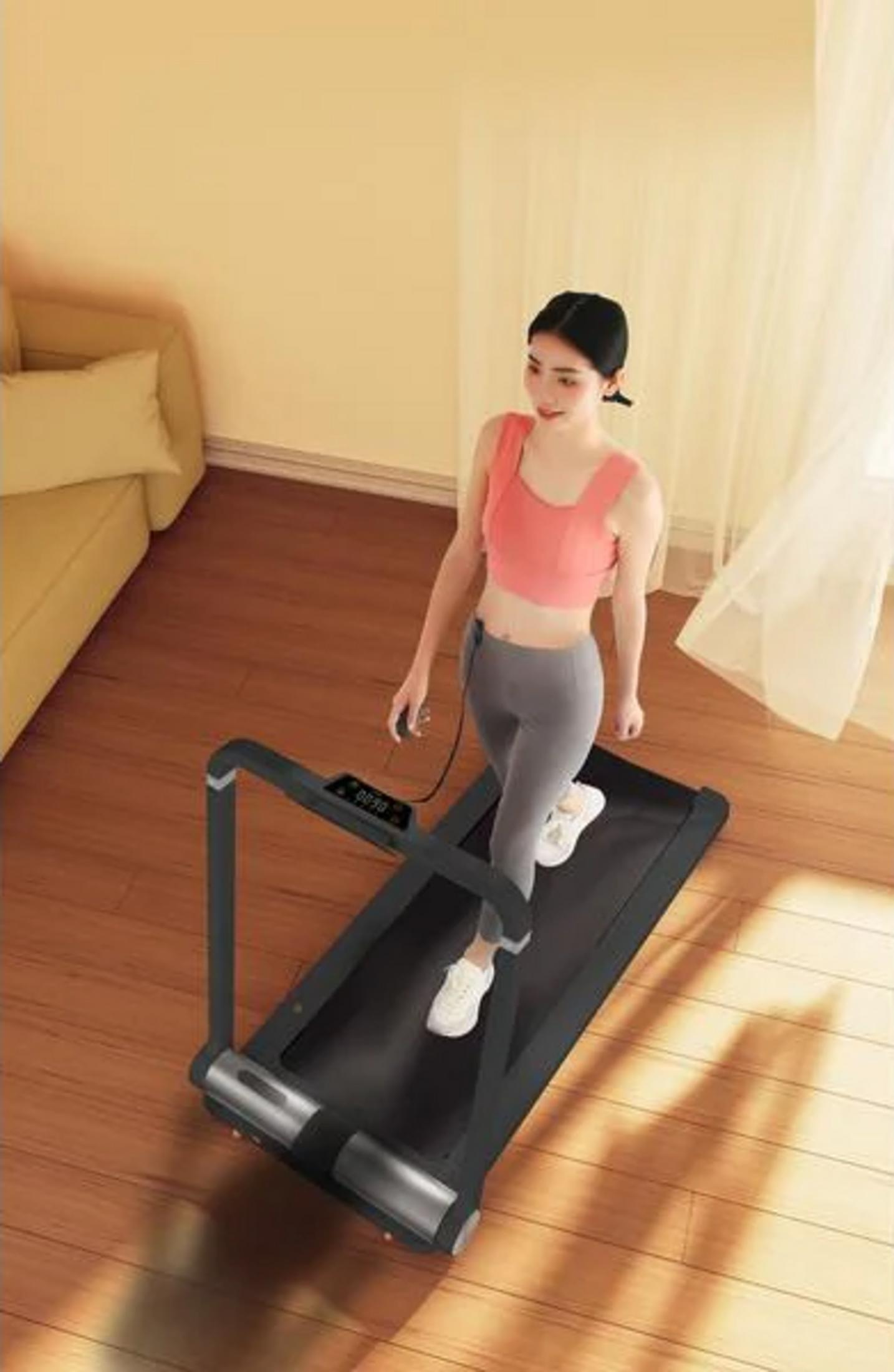 Kobieta ćwiczy na bieżni w jasnym pokoju z drewnianą podłogą.