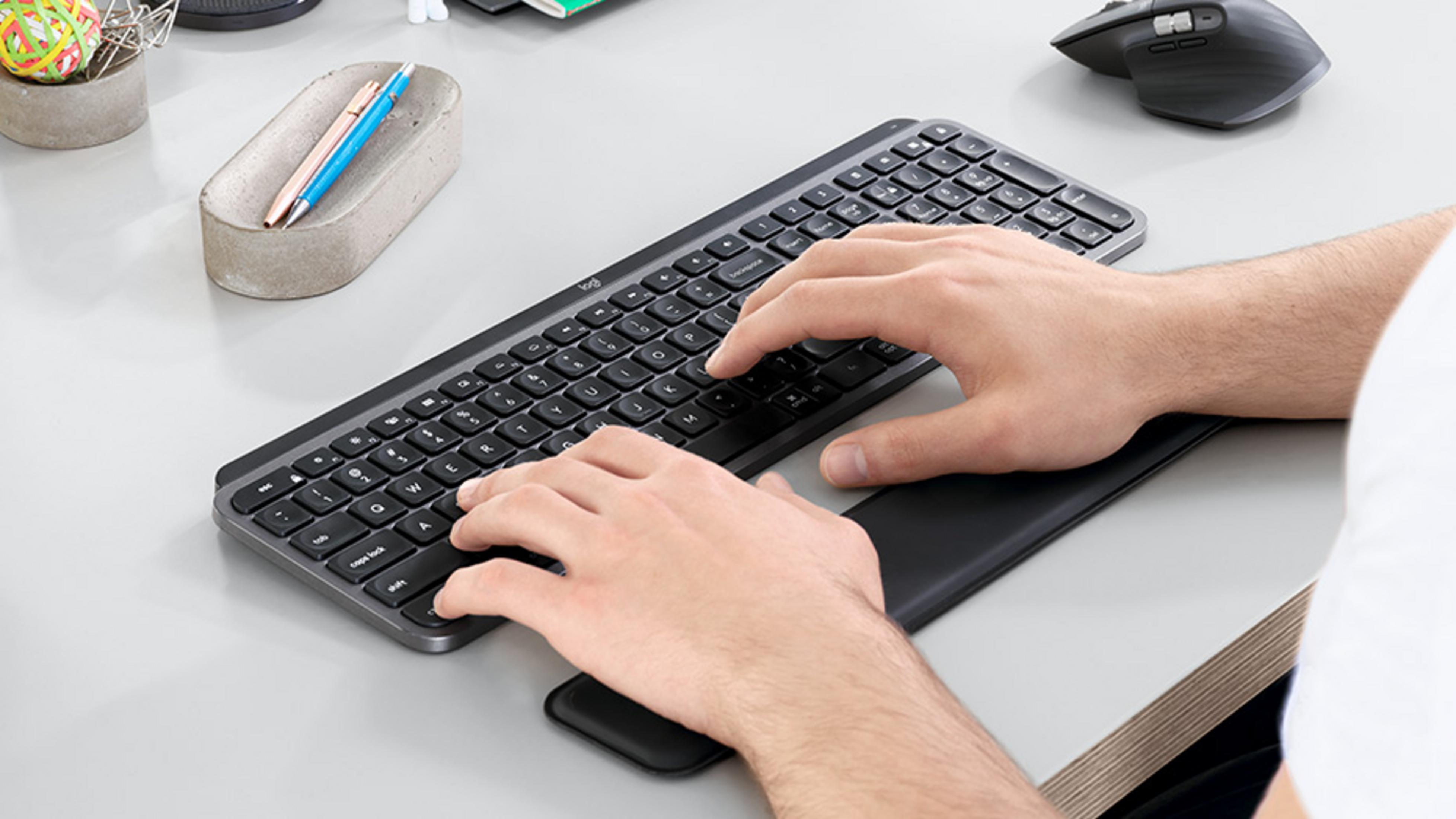 Mani che digitano su una tastiera scura, mouse nelle vicinanze.