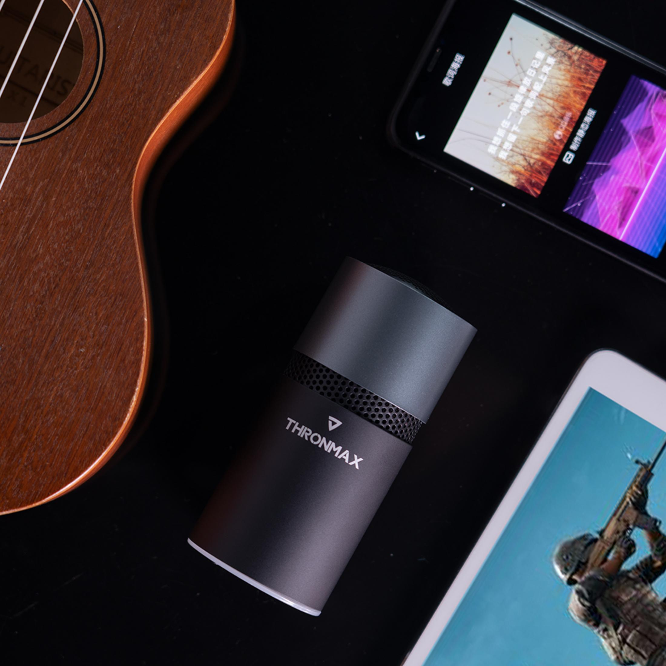Ukulele, altoparlante nero, telefono e tablet mostrano immagini.