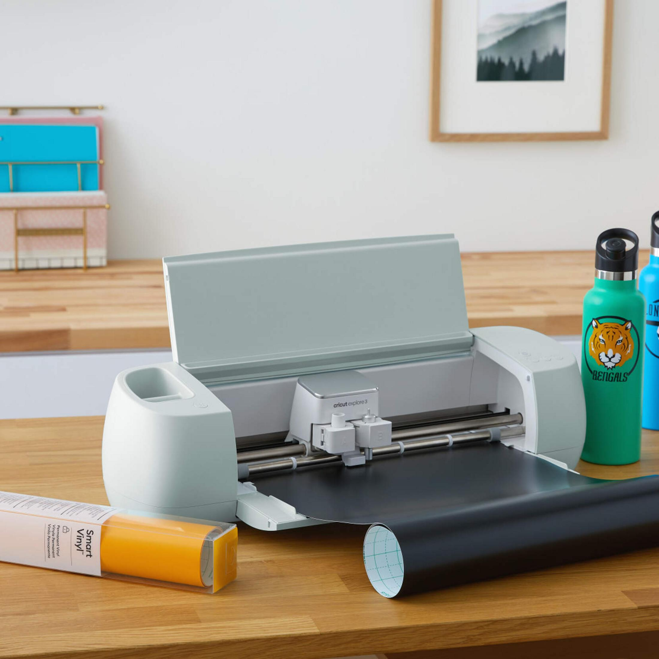 Ein Schneideplotter mit schwarzer Folie, daneben eine gelbe Vinylrolle und zwei Wasserflaschen.