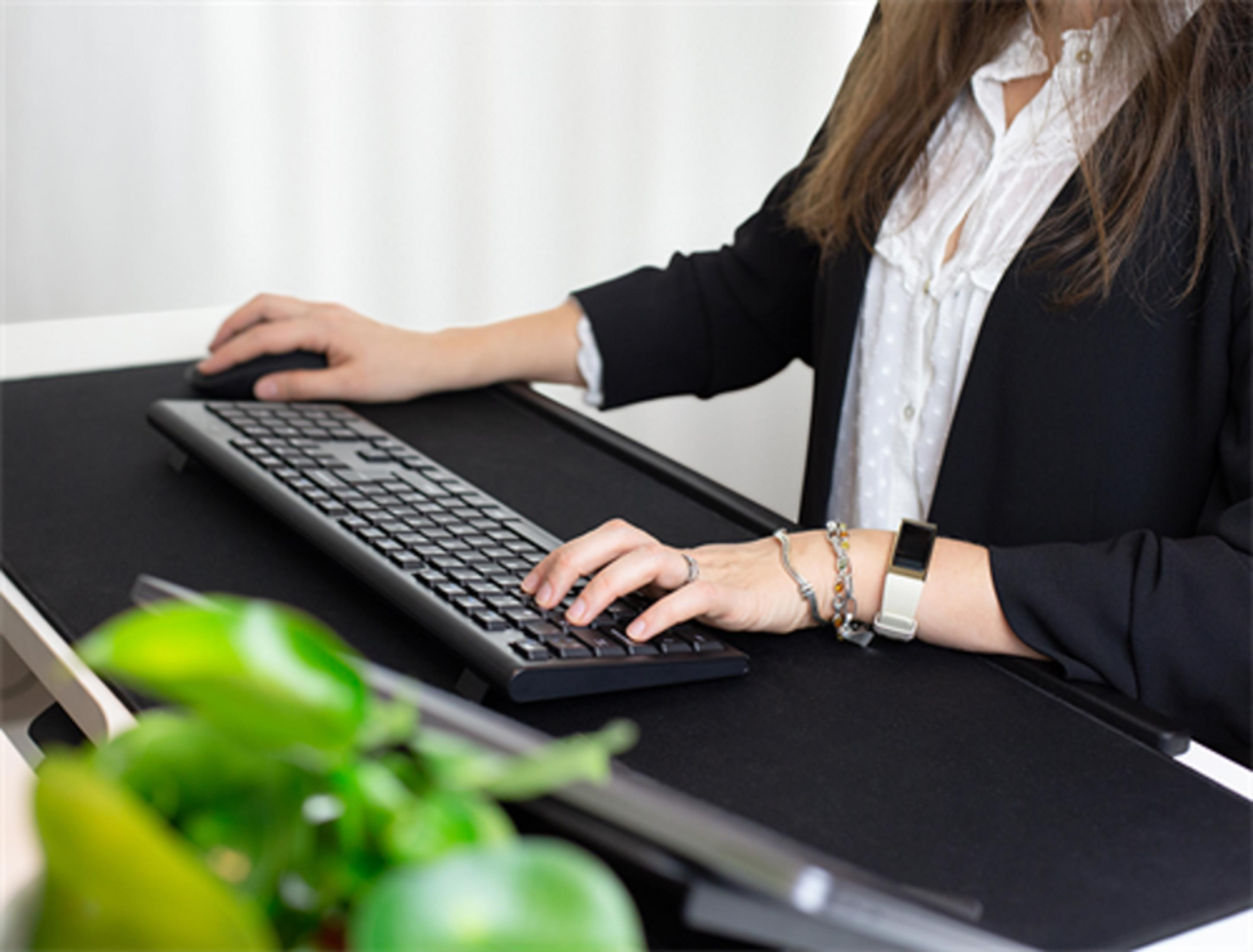 Eine Person tippt auf einer Tastatur, daneben eine Maus und grünes Gemüse.