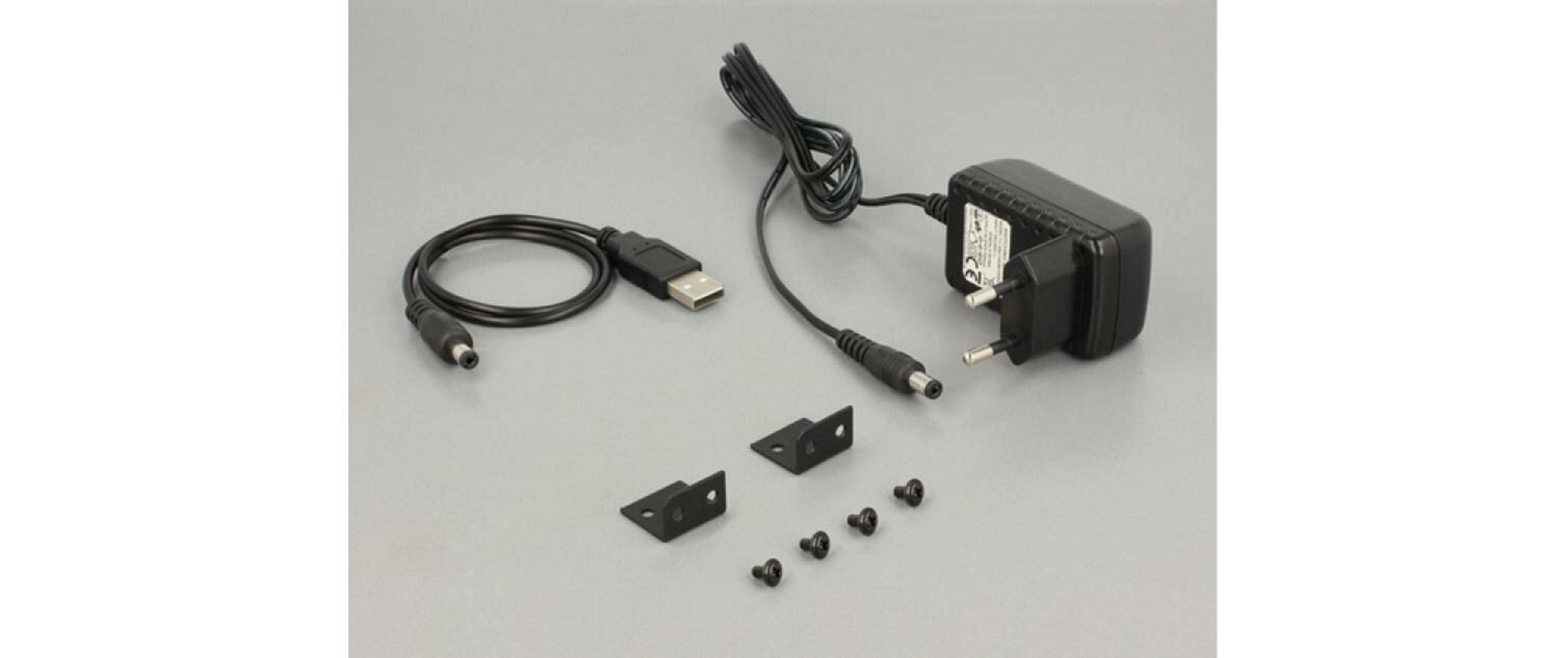 Ein schwarzer Netzadapter mit USB-Kabel, Halterungen und Schrauben auf grauem Untergrund.