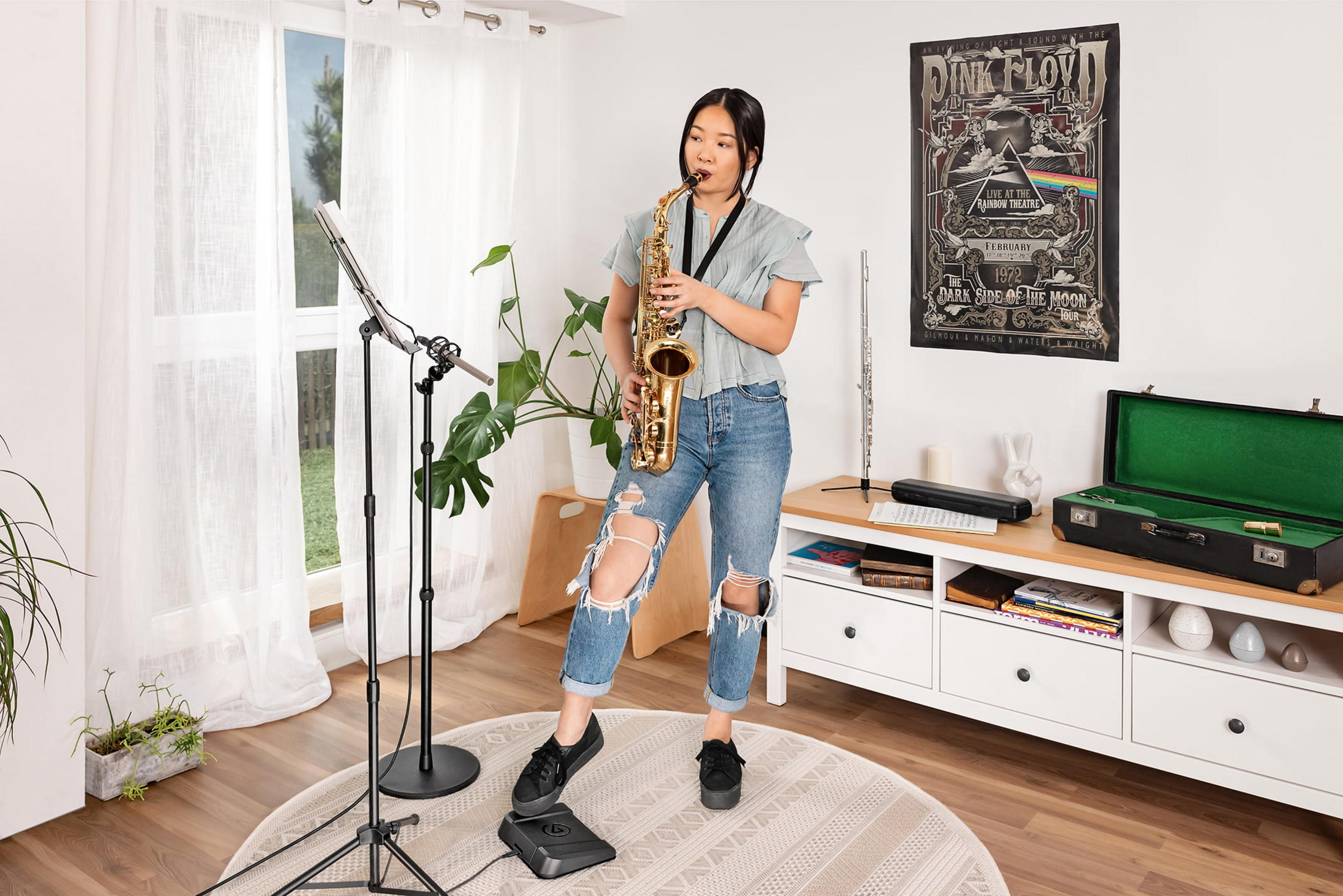Eine Frau spielt Saxophon in einem Raum mit einem Pink Floyd Poster.