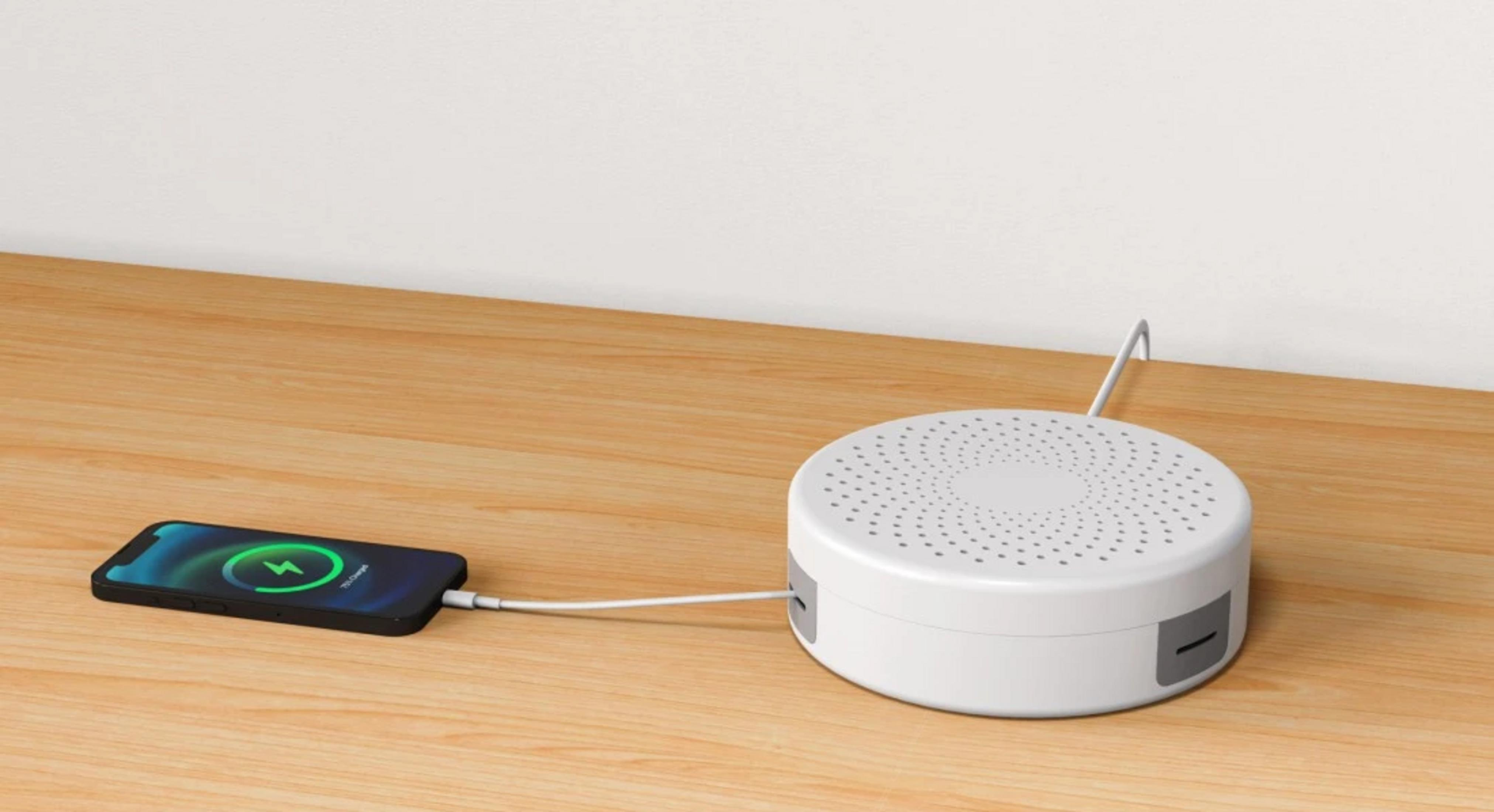 Un caricabatterie bianco e rotondo collegato a un iPhone su un tavolo di legno.