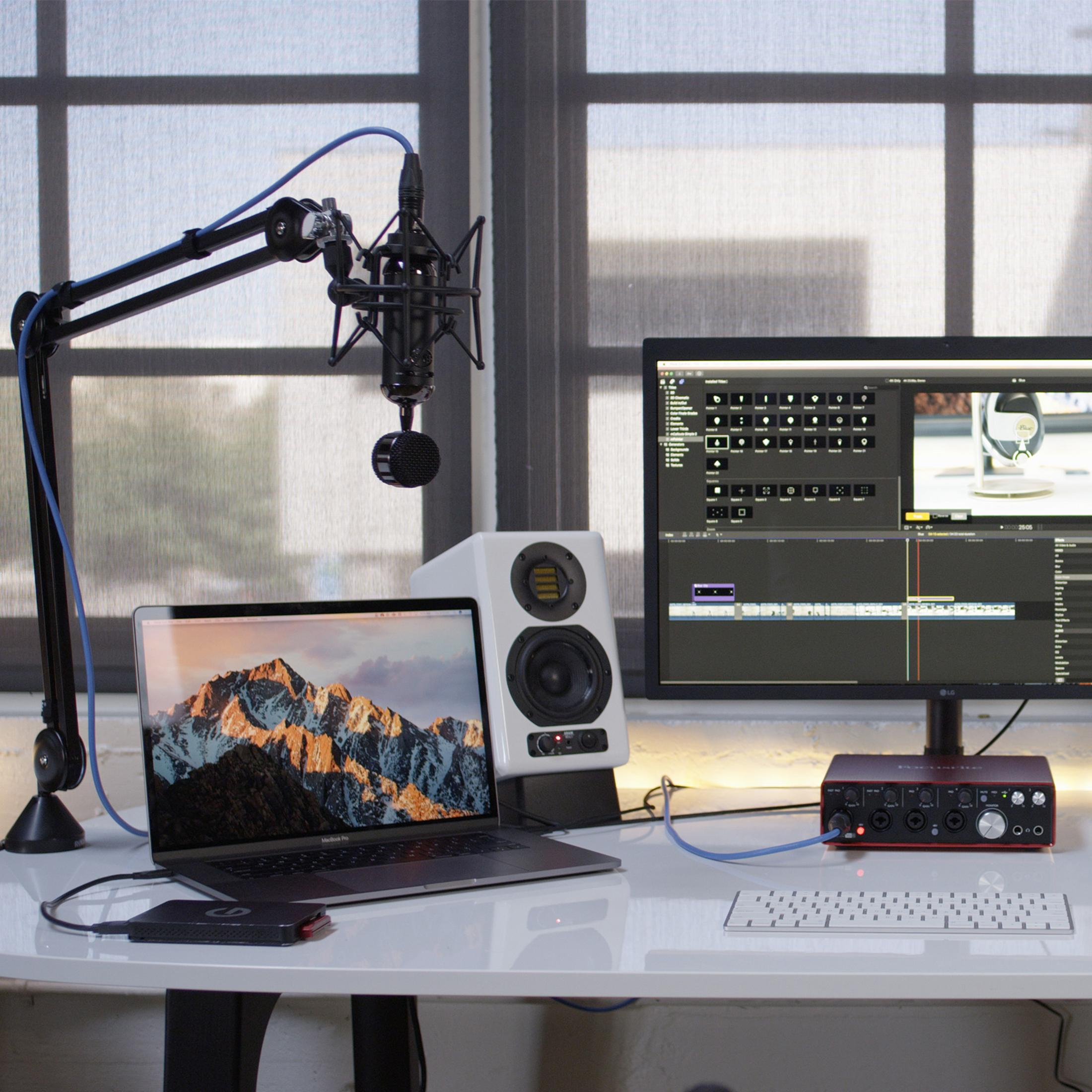 Ein Schreibtisch mit einem Laptop, Monitor, Mikrofon und Audio-Interface.