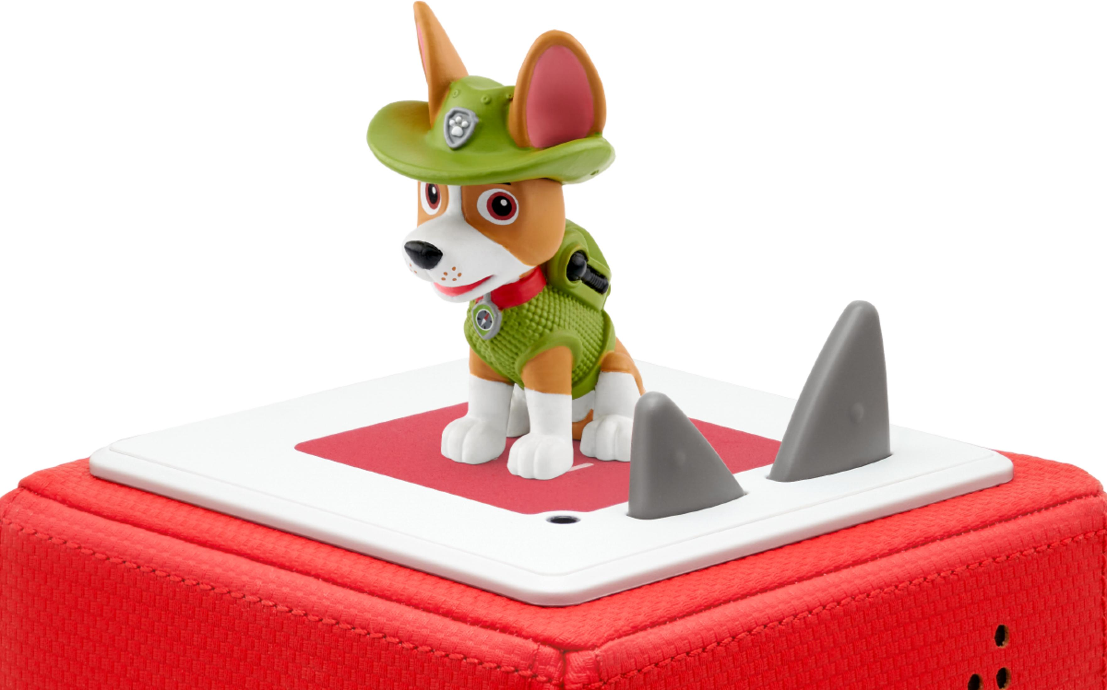 Ein Hundespielzeug mit grütem Hut und Weste steht auf einem roten Würfel.