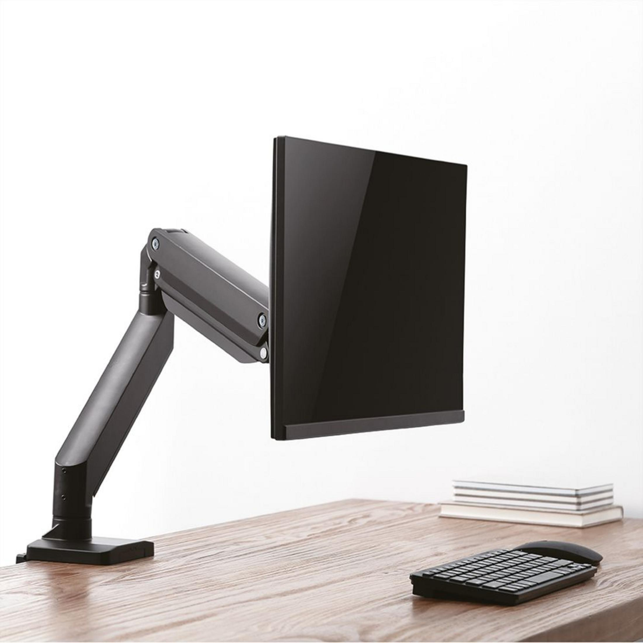 Ein schwarzer Monitorarm hält einen schwarzen Monitor über einem Schreibtisch mit Tastatur und Büchern.