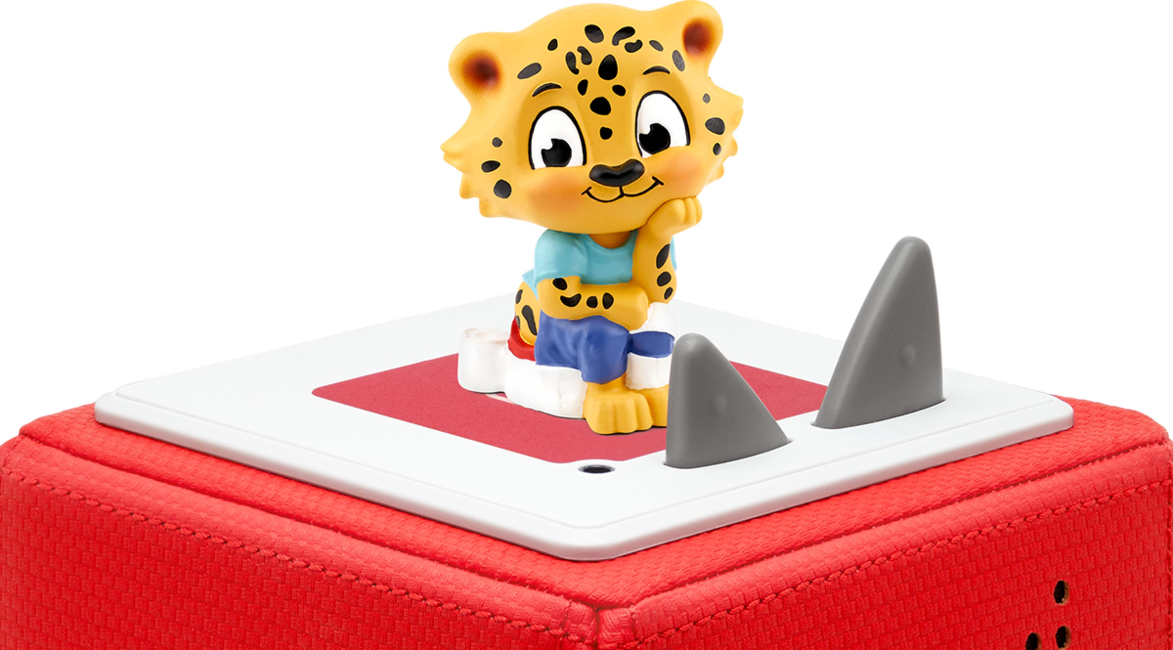 Ein Leoparden-Spielzeug sitzt auf einem roten Kasten mit weißen und roten Oberflächen.