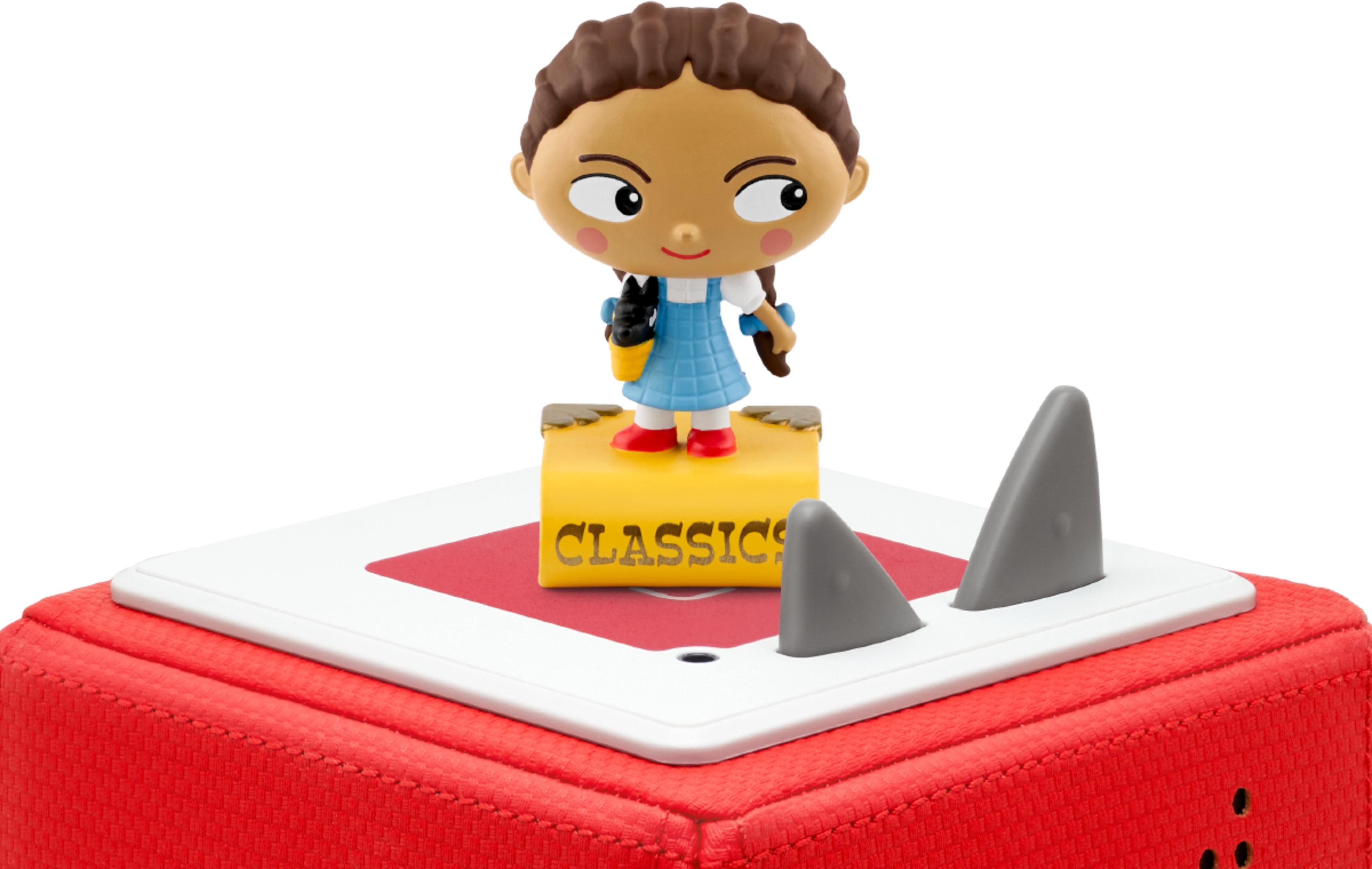 Dorothy-Figur auf gelbem Buch mit Hai-Flossen auf rotem Kasten.