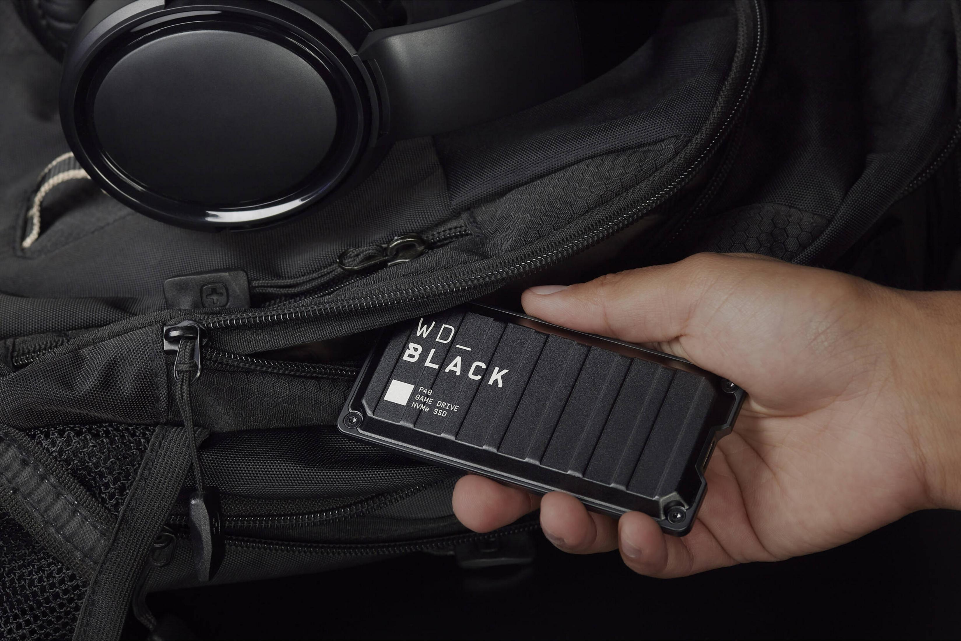 Ręka trzyma czarny dysk SSD WD_BLACK P40 w czarnej torbie z słuchawkami.