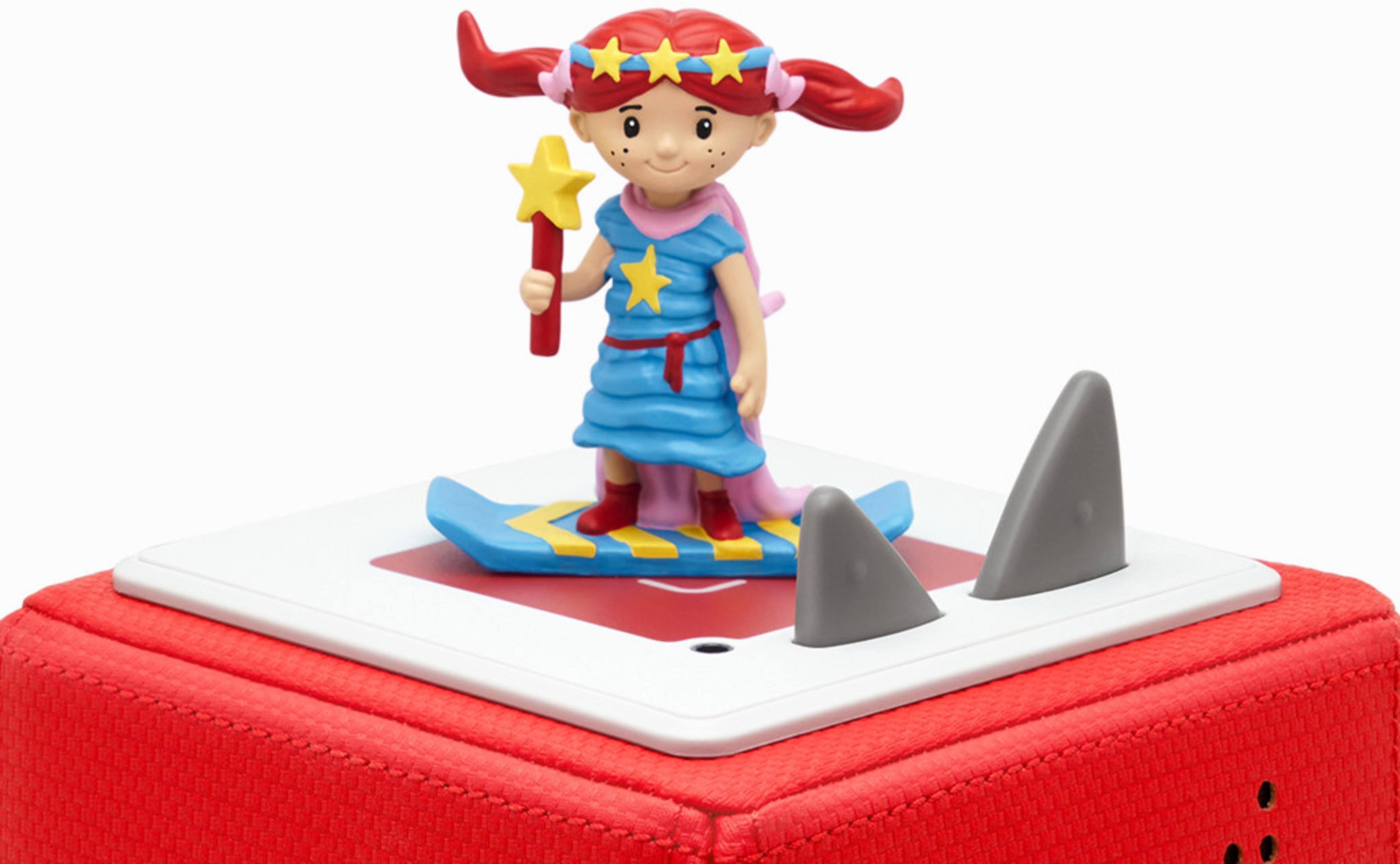 Figur eines Mädchens auf einem Surfbrett mit Sternenstab, auf rotem Würfel.