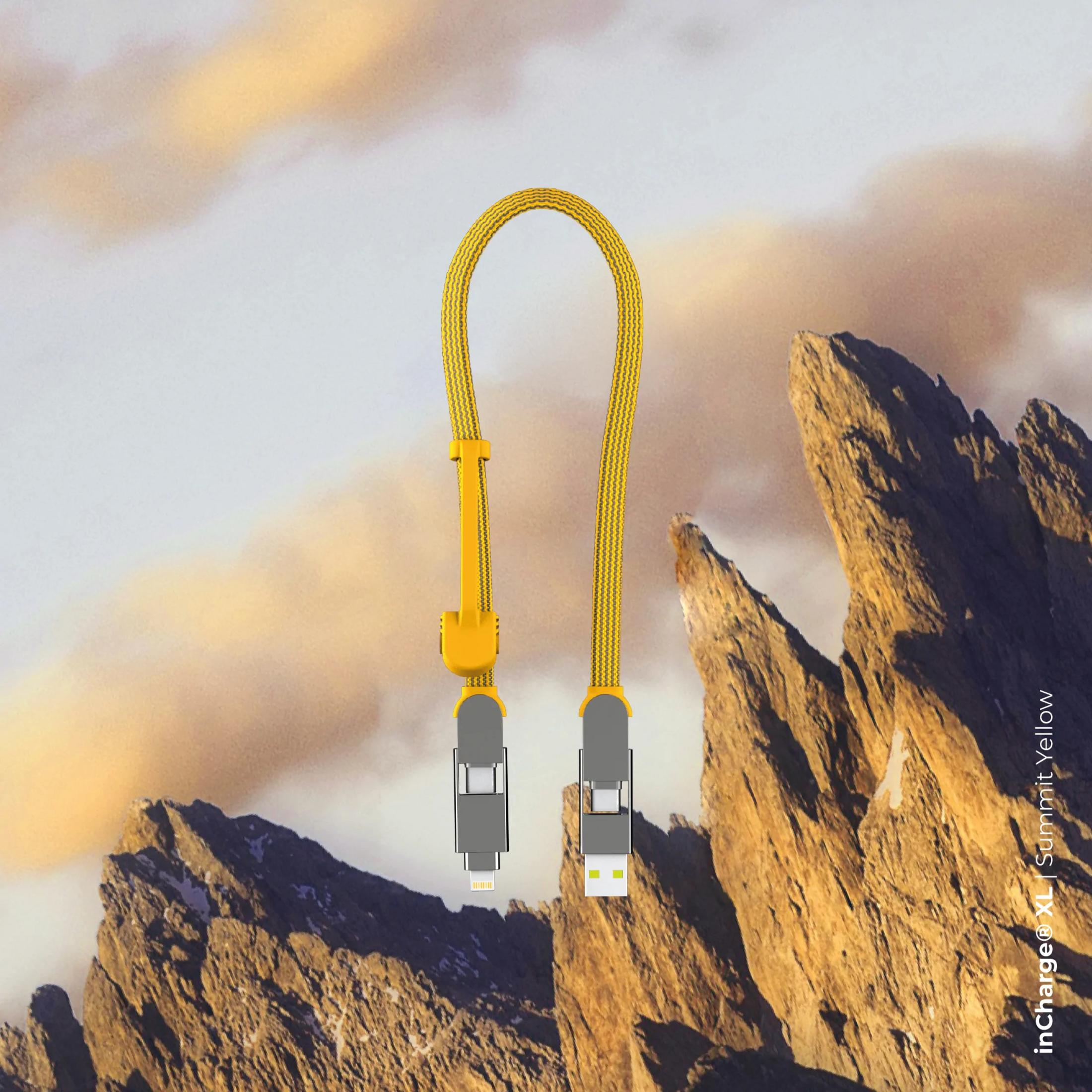 Gele oplaadkabel met USB-C en Lightning connectoren tegen rotsachtige bergen.