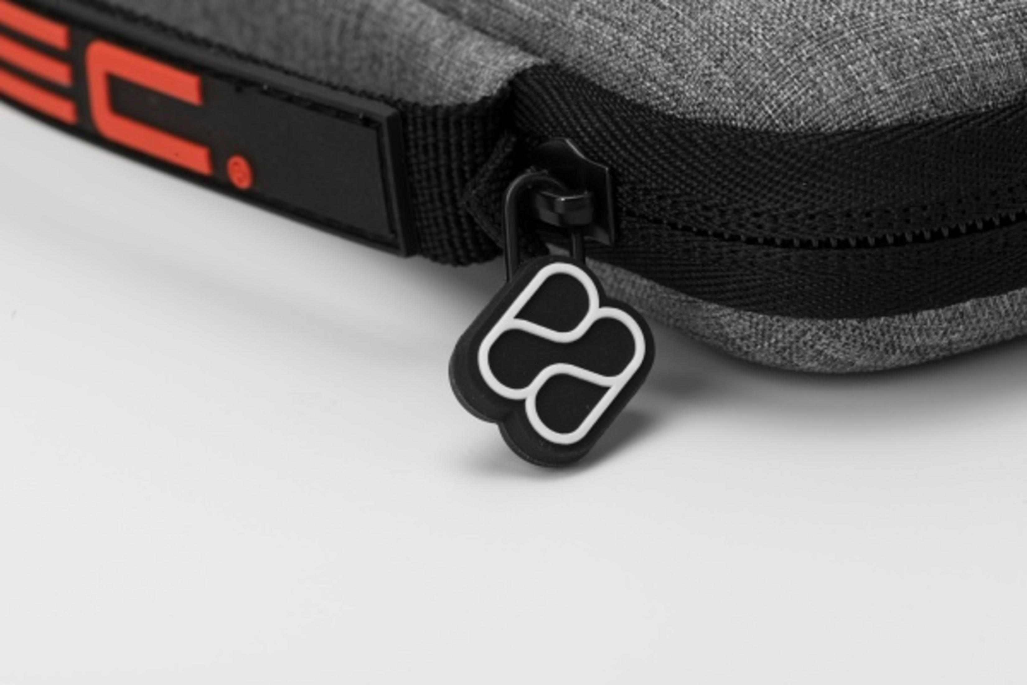 Bolso de tela gris con cremallera y tirador con logo.