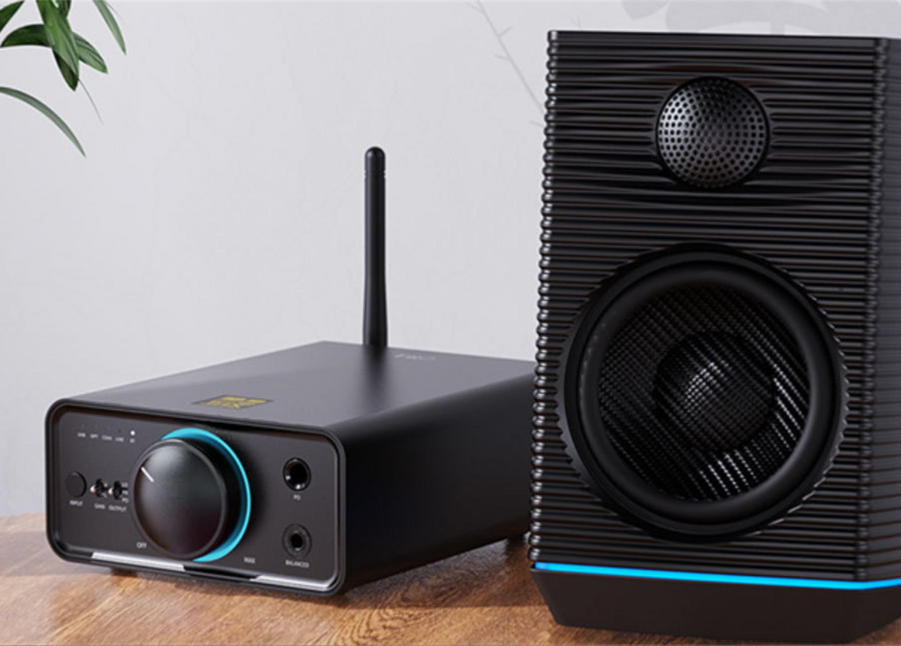 Amplificador negro con mando y antena junto a un altavoz negro con iluminación azul.