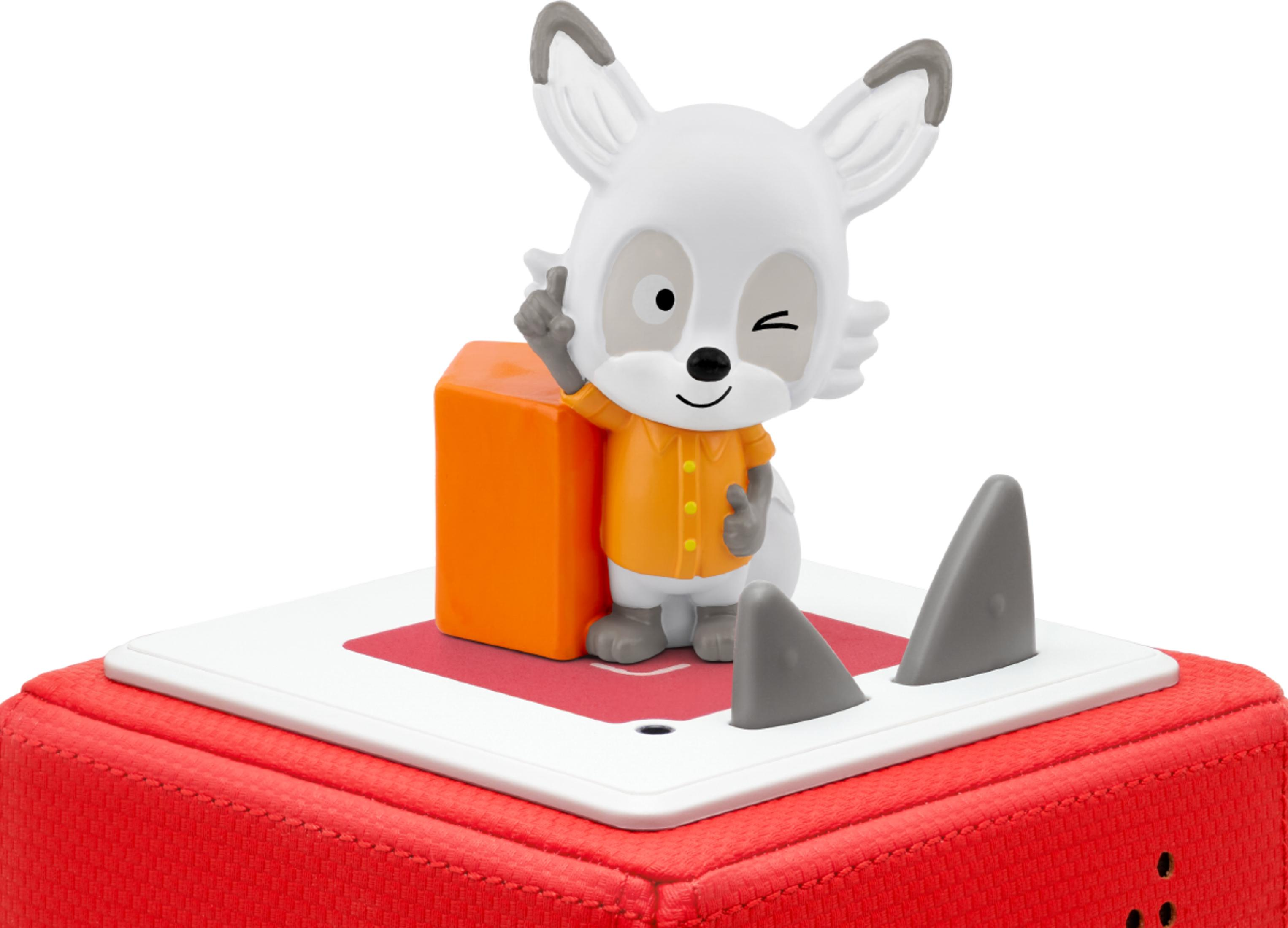 Un renard jouet blanc en tenue orange se tient sur une base rouge avec des ailerons de requin.