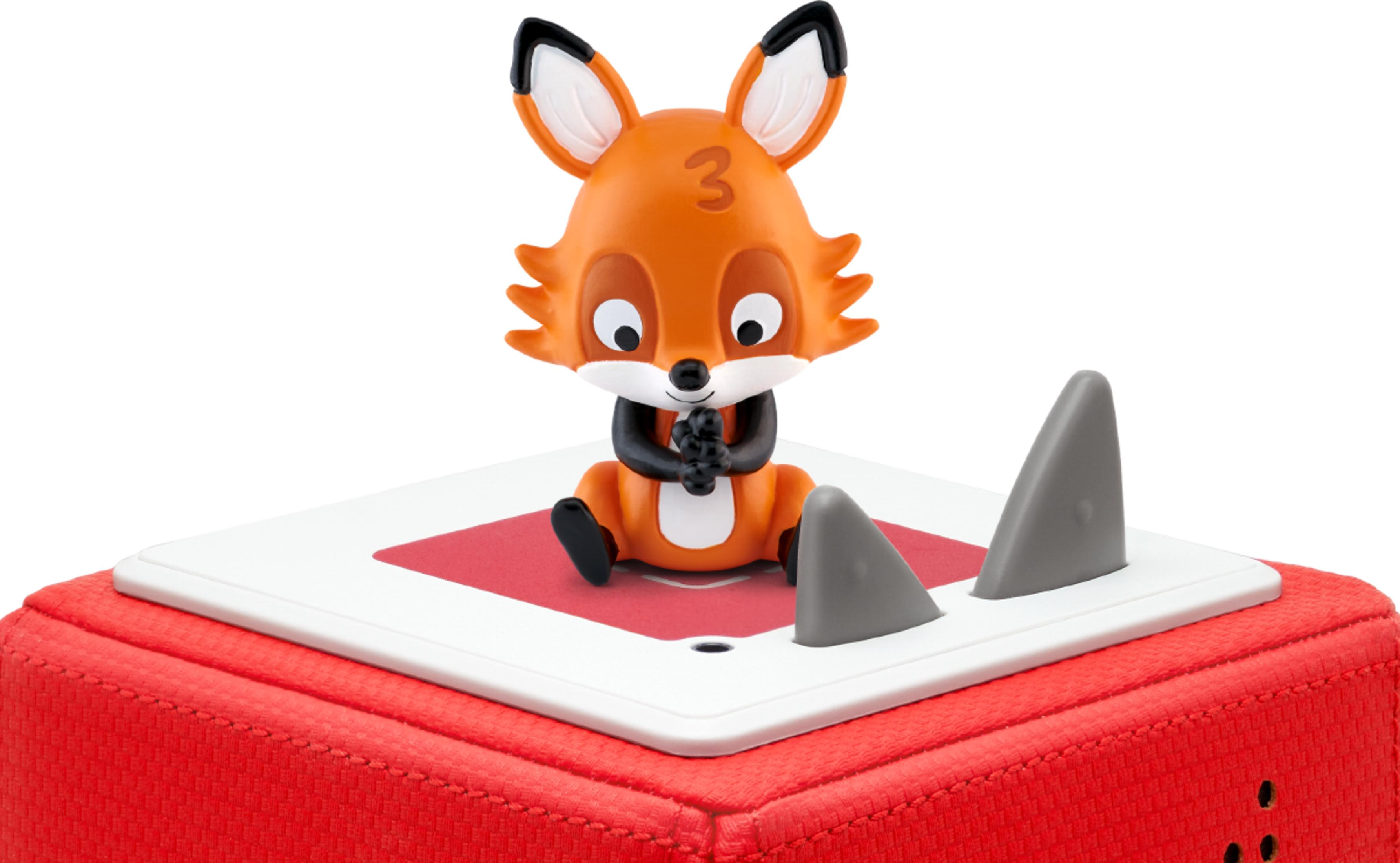 Ein orangefarbener Fuchs sitzt auf einem roten Würfel mit grauen Haifischflossen.