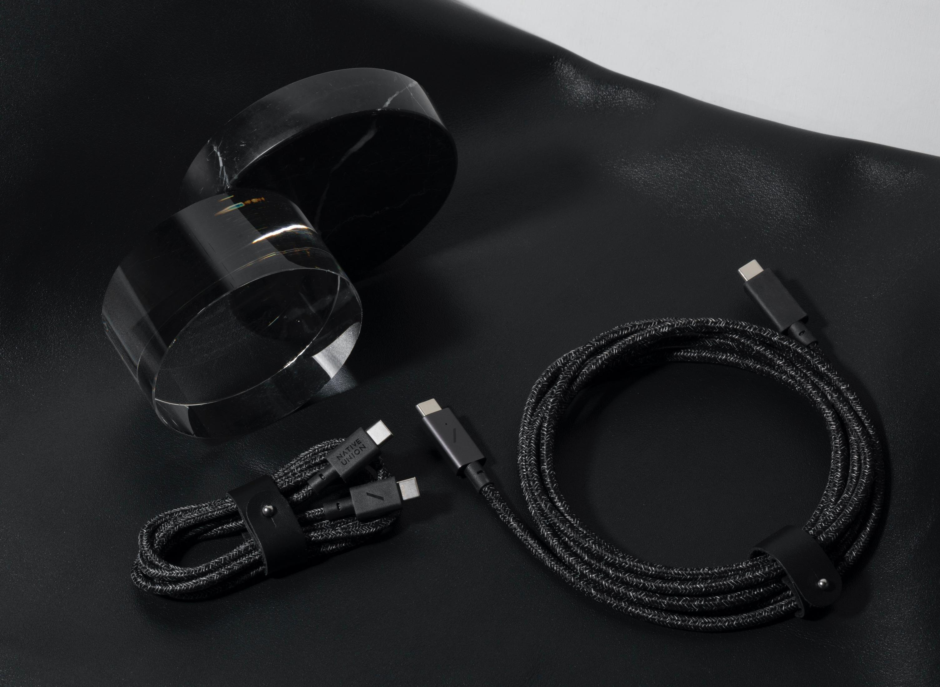 Due cavi neri con connettori USB-C giacciono accanto a due contenitori neri rotondi.