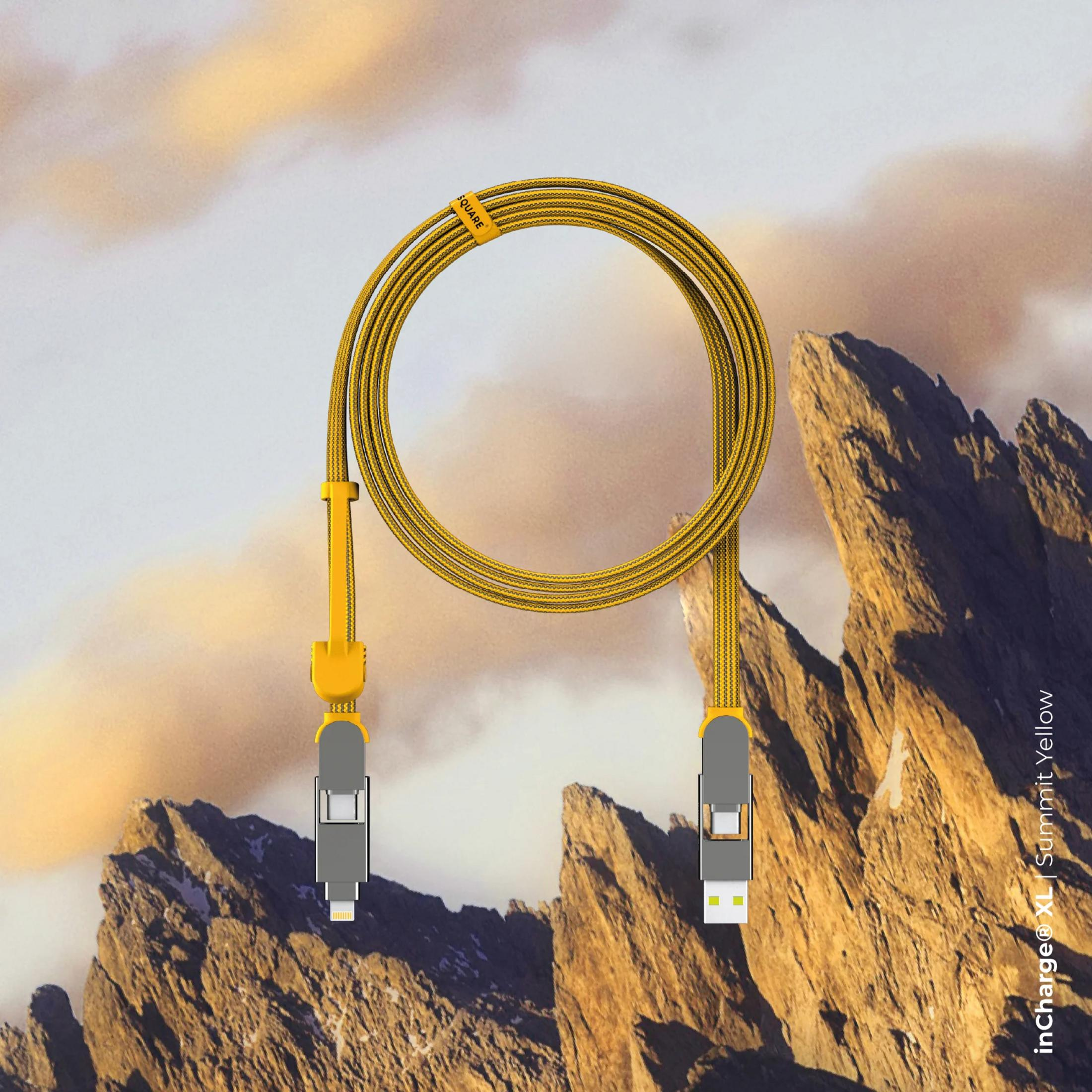 Een gele oplaadkabel met twee connectoren wordt getoond tegen een berglandschap.