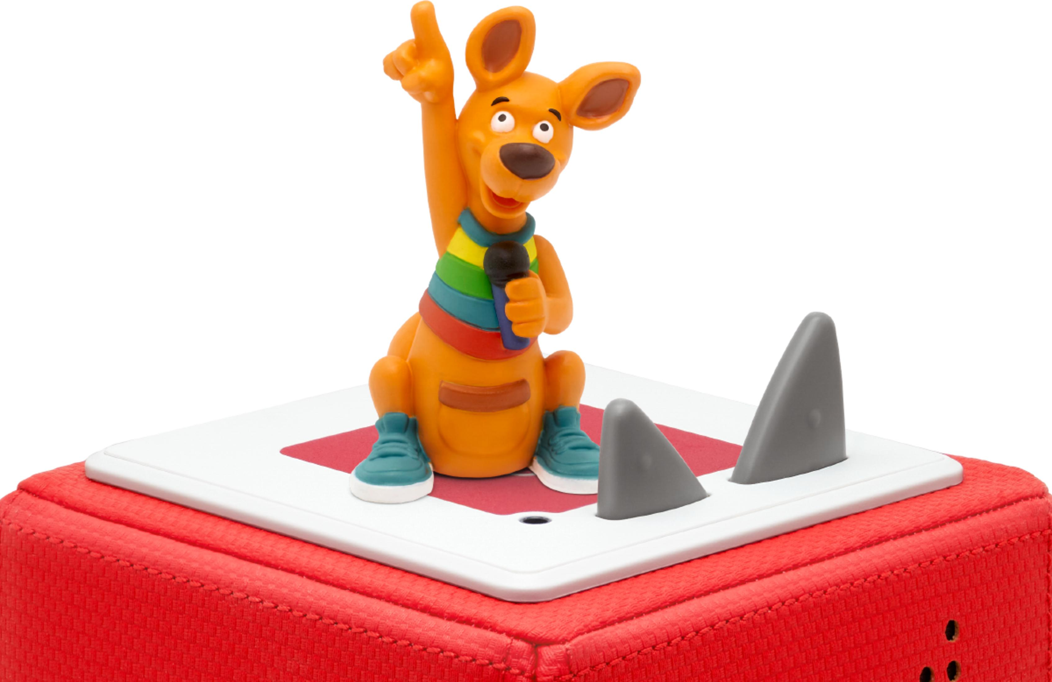 Ein orangefarbener Känguru-Spielzeug hält ein Mikrofon, steht auf einem roten Würfel.