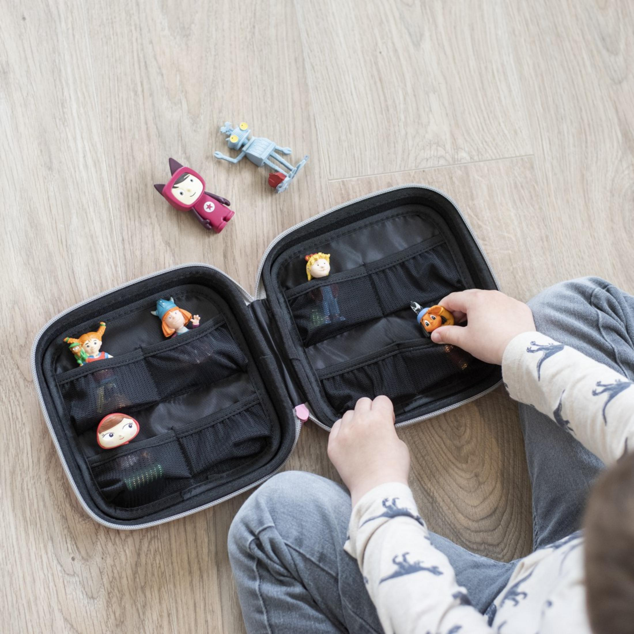 Ein Kind sortiert Spielzeugfiguren in einer geöffneten Federtasche auf Holzboden.