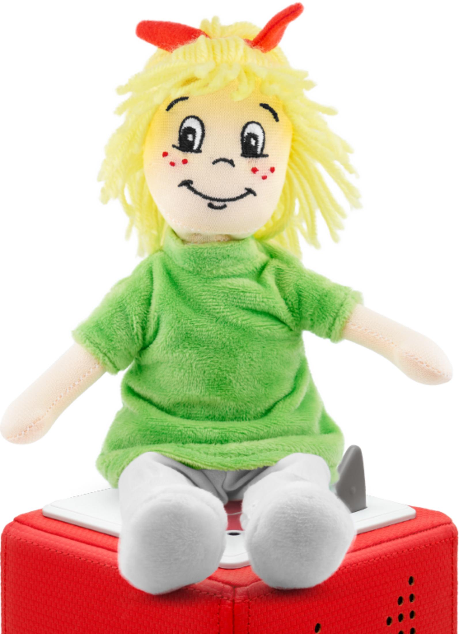 Stoffpuppe mit blonden Haaren, grünem Oberteil und weißer Hose sitzt auf roter Box.