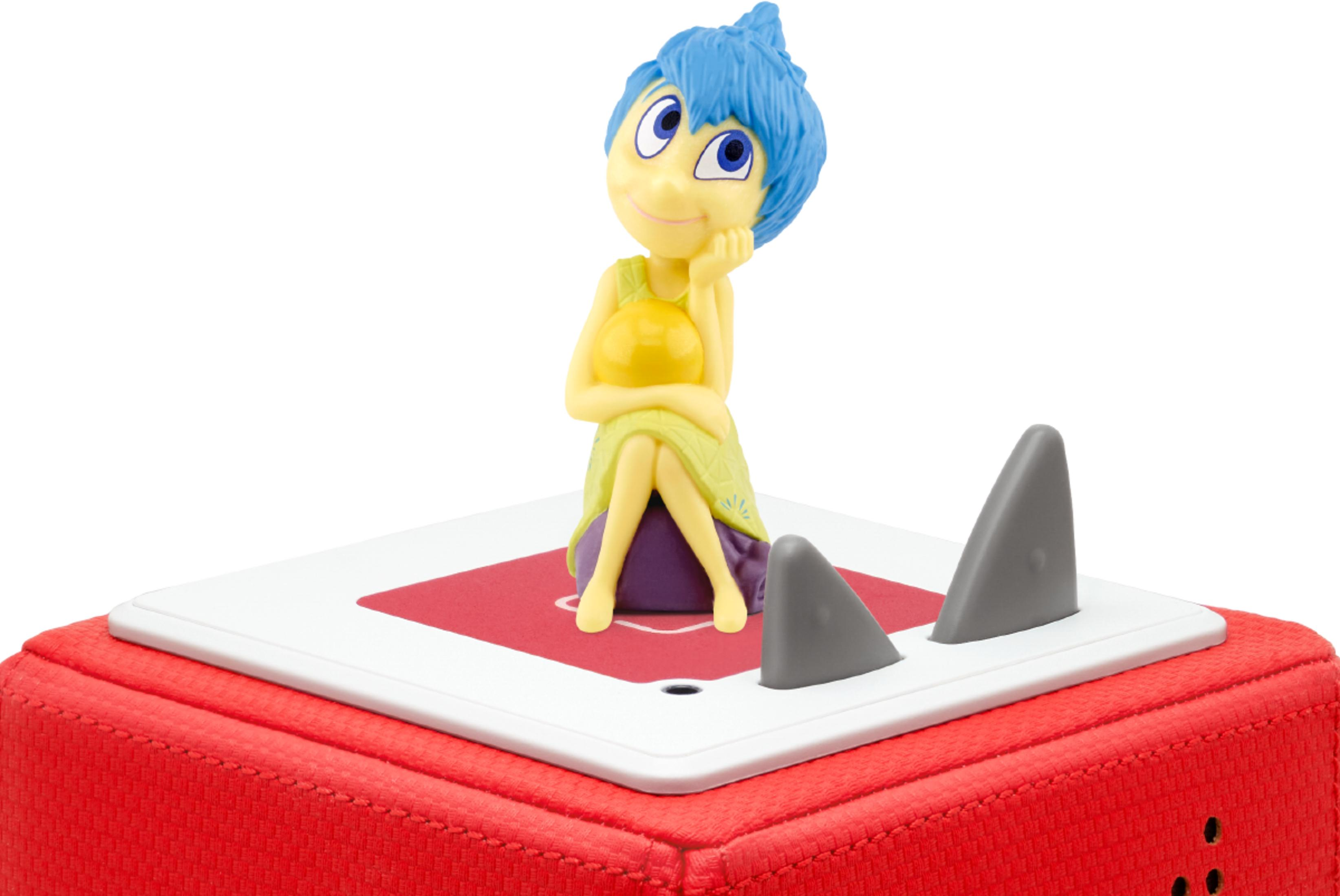 Eine Figur mit blauen Haaren sitzt auf einem roten und weißen Objekt mit Haifischflossen.