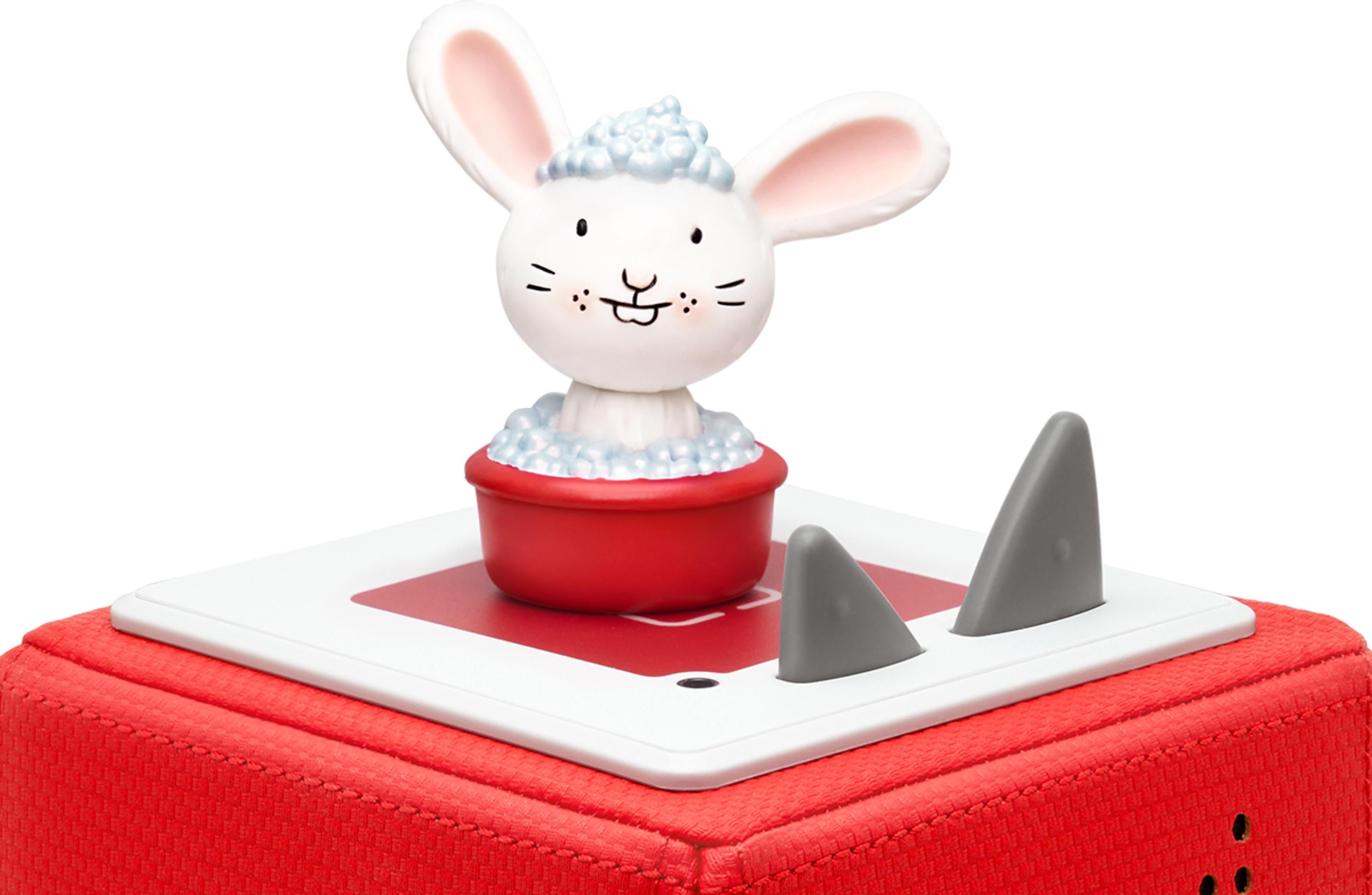 Ein Spielzeug-Hase in einer roten Wanne auf einem roten Würfel mit grauen Haifischflossen.