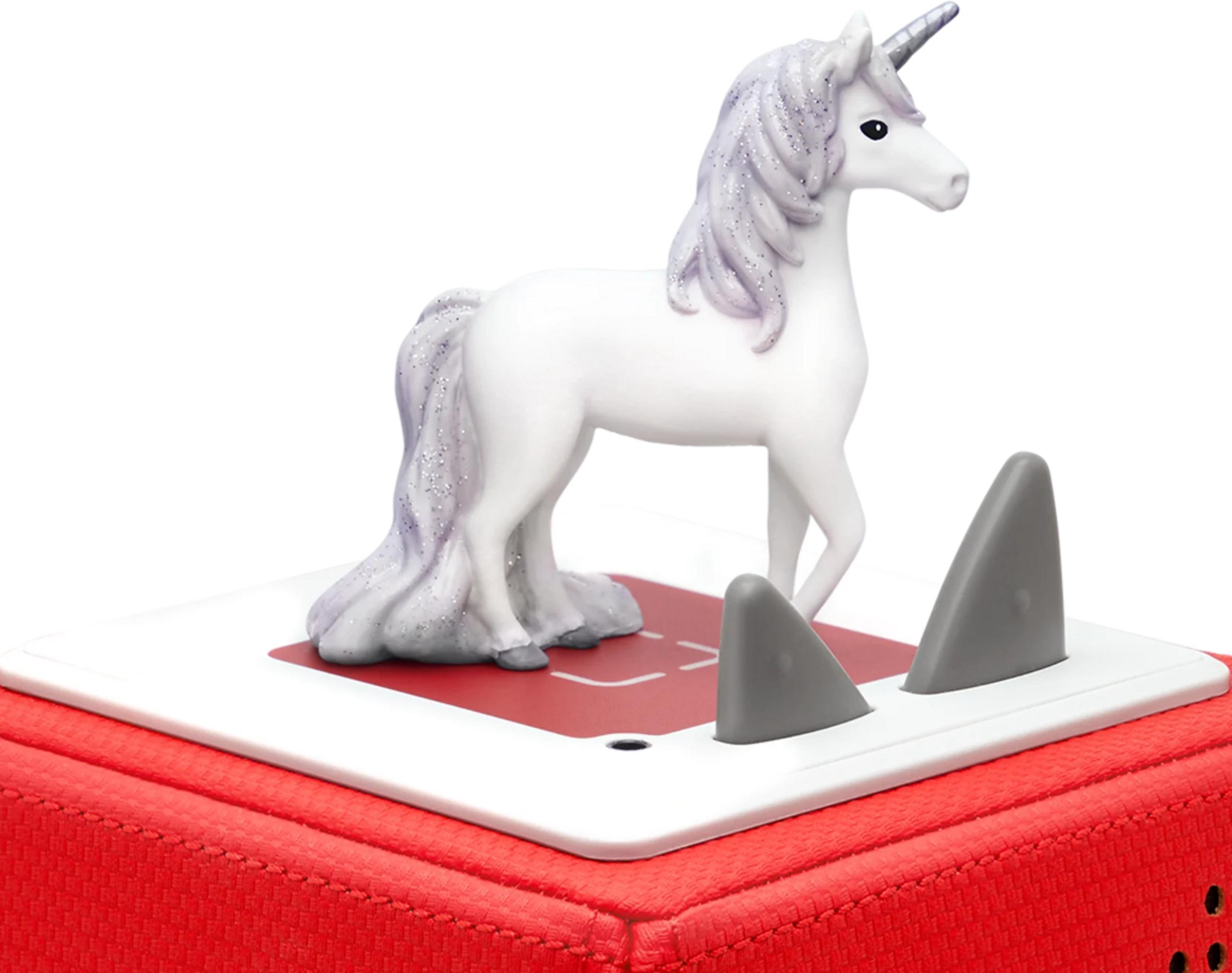 Une licorne blanche à crinière violette pailletée se tient sur une boîte rouge avec des ailerons de requin.