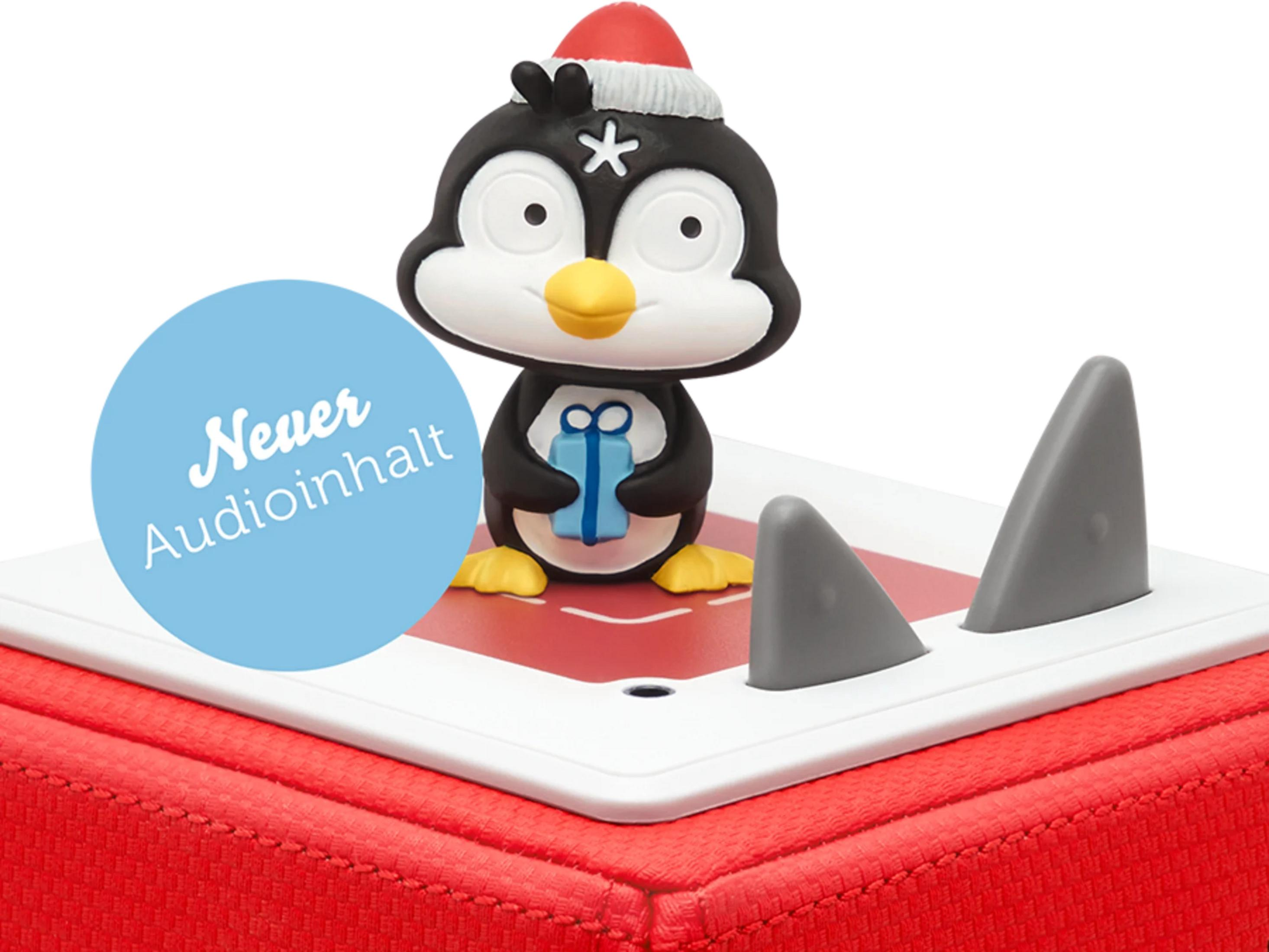 Ein Weihnachtspinguin hält ein Geschenk. Daneben sind zwei graue Haifischflossen.