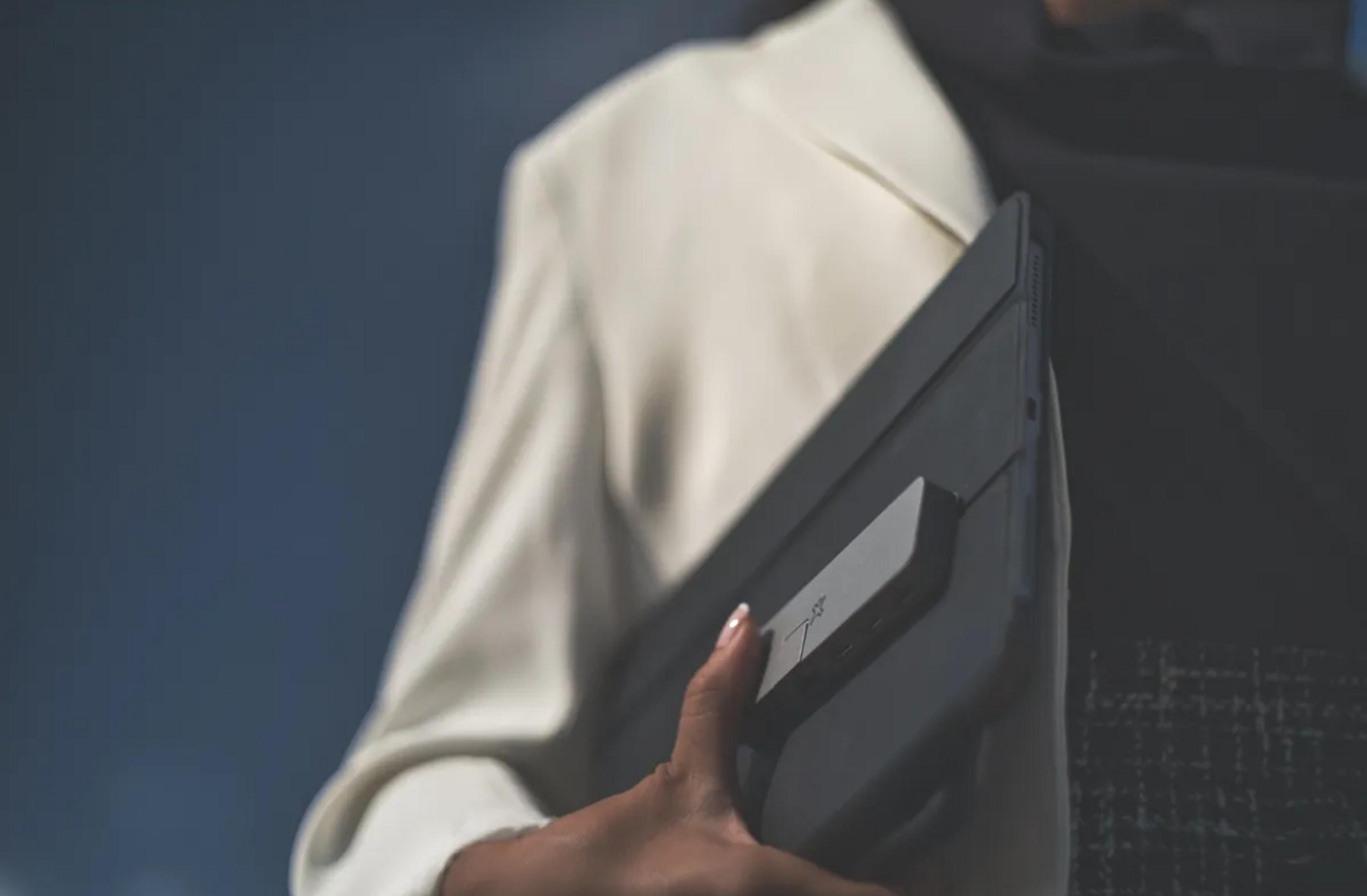 Una mano tiene un tablet nero con custodia su sfondo blu.