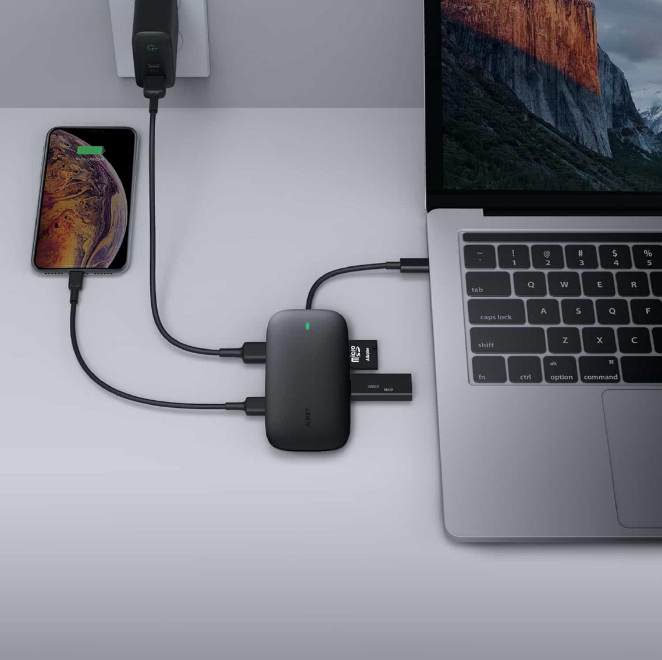Ein schwarzer USB-C-Hub verbindet ein iPhone und einen Laptop. Eine SD-Karte ist eingesetzt.