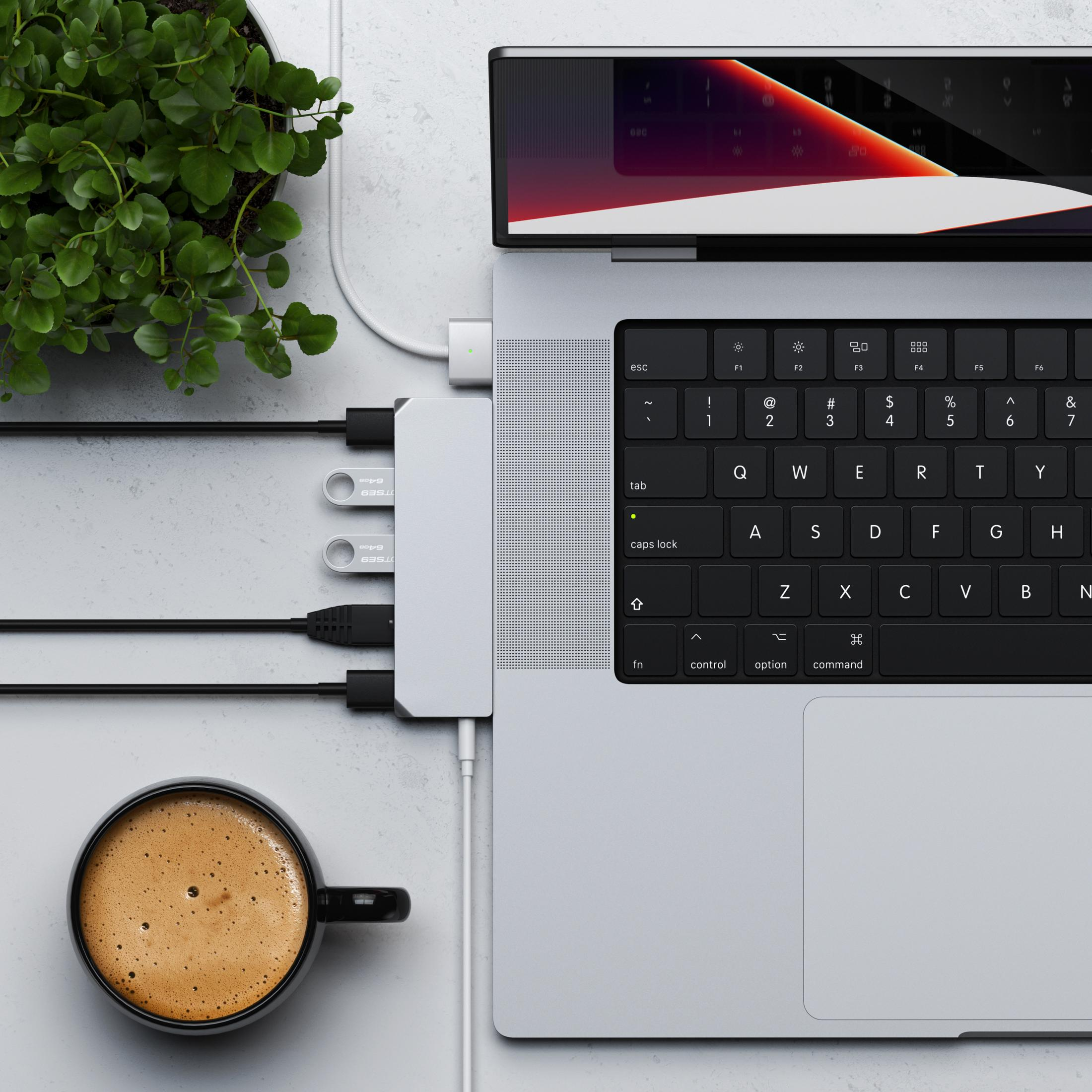 Ein Laptop mit USB-Hub, Kaffeetasse, Pflanze und USB-Sticks.