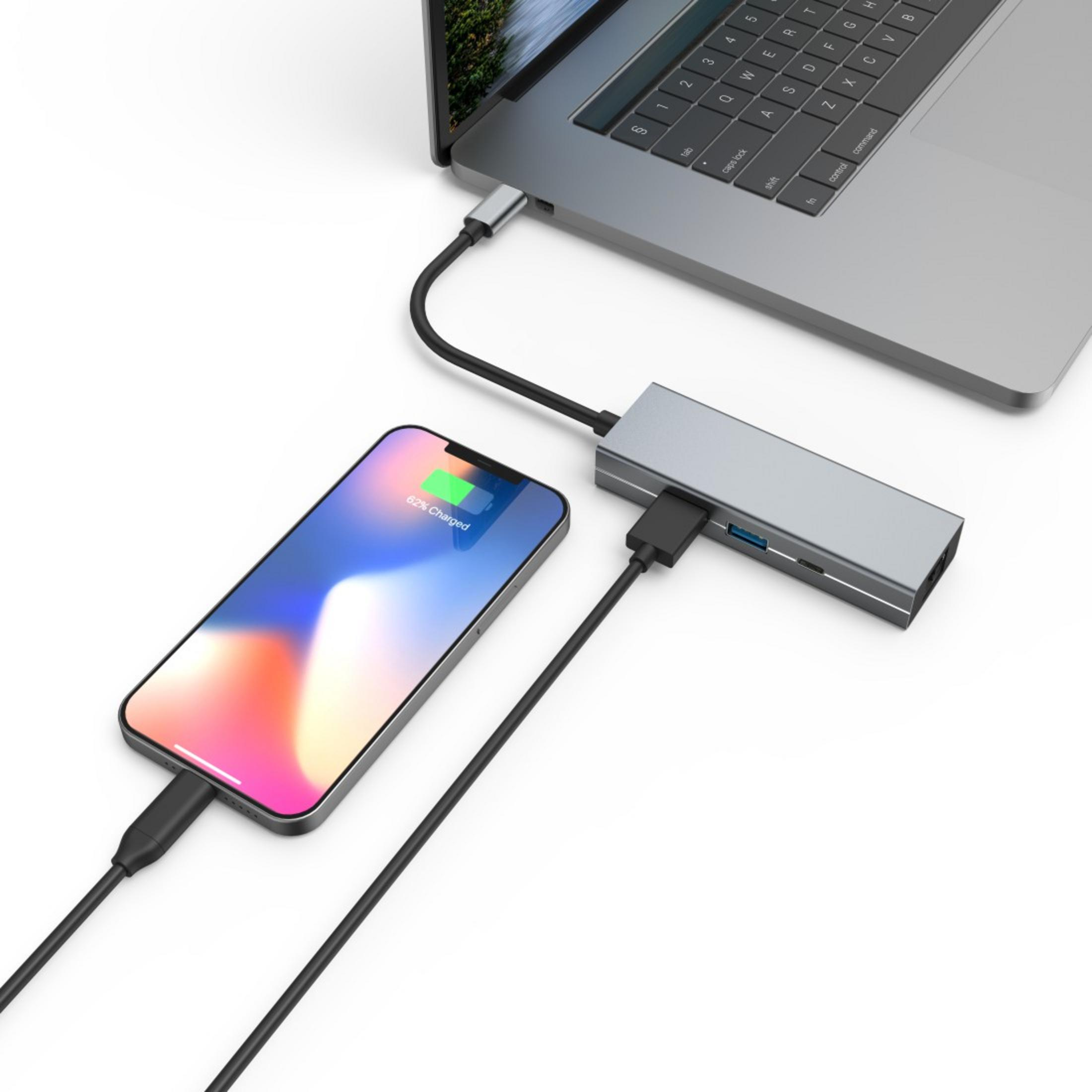 Laptop jest podłączony do huba USB-C, który ładuje smartfon.