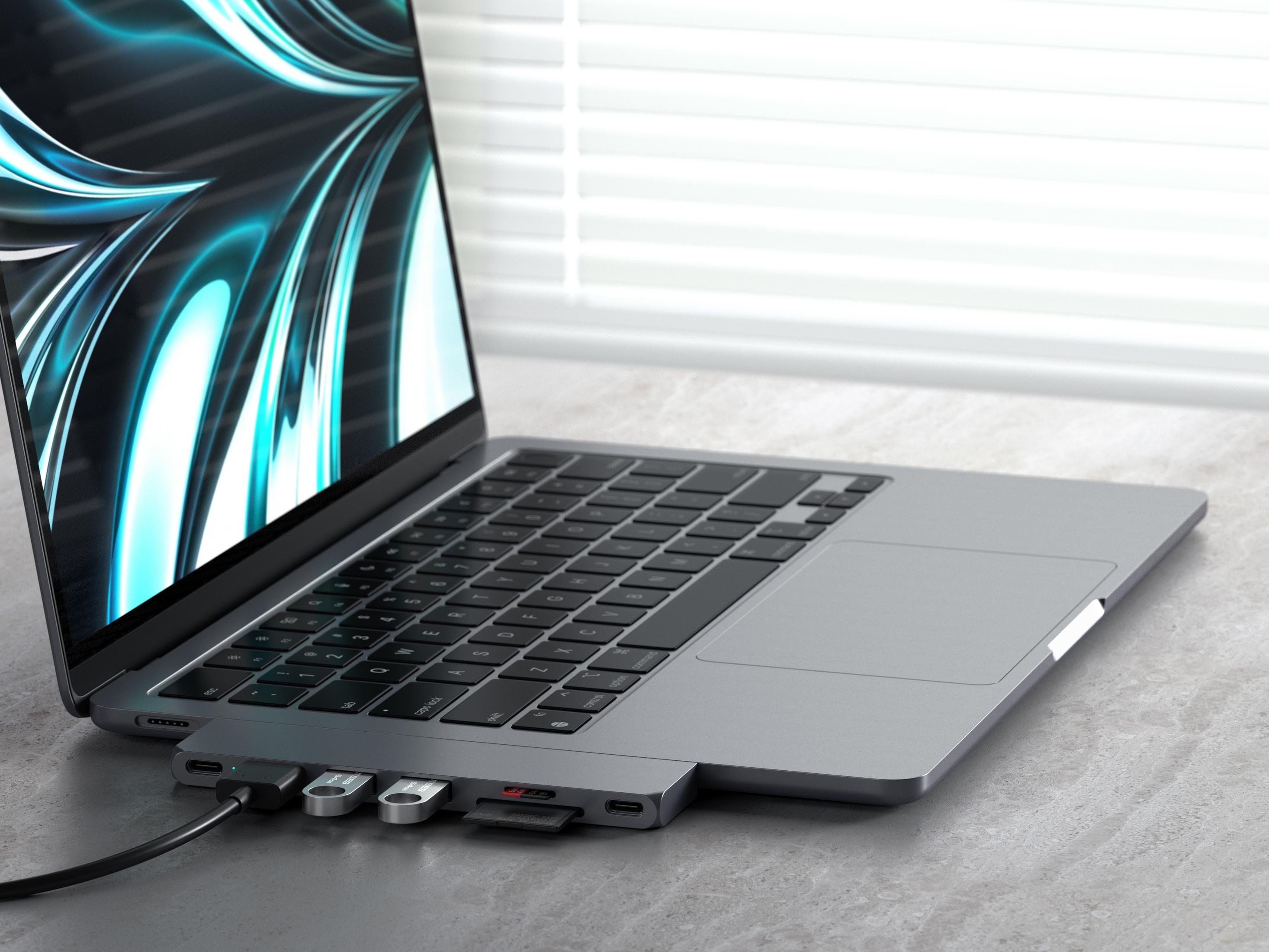 Un portátil con un hub, unidades USB y tarjeta SD conectados.