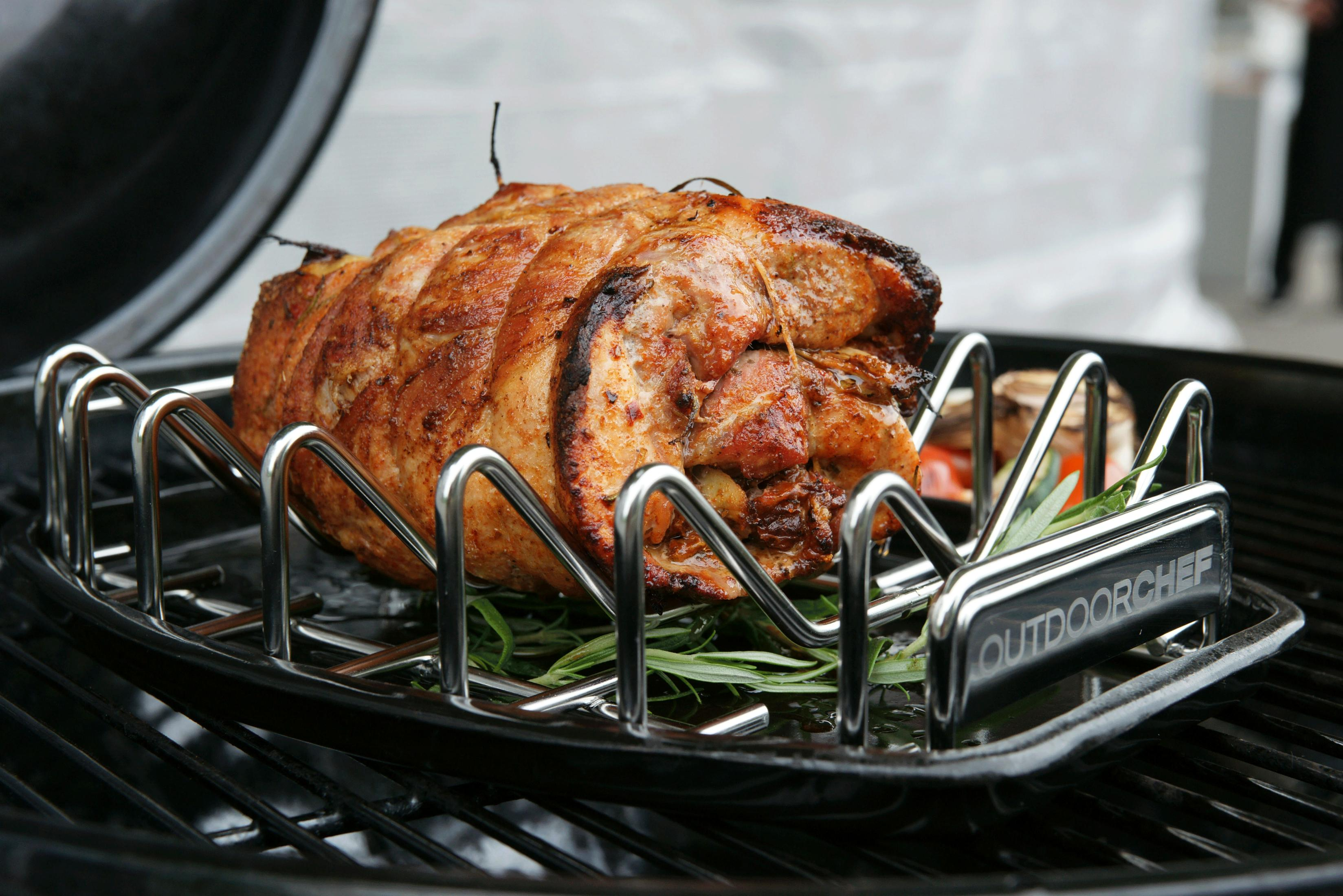 Un arrosto abbrustolito su una griglia con erbe aromatiche, all'aperto.