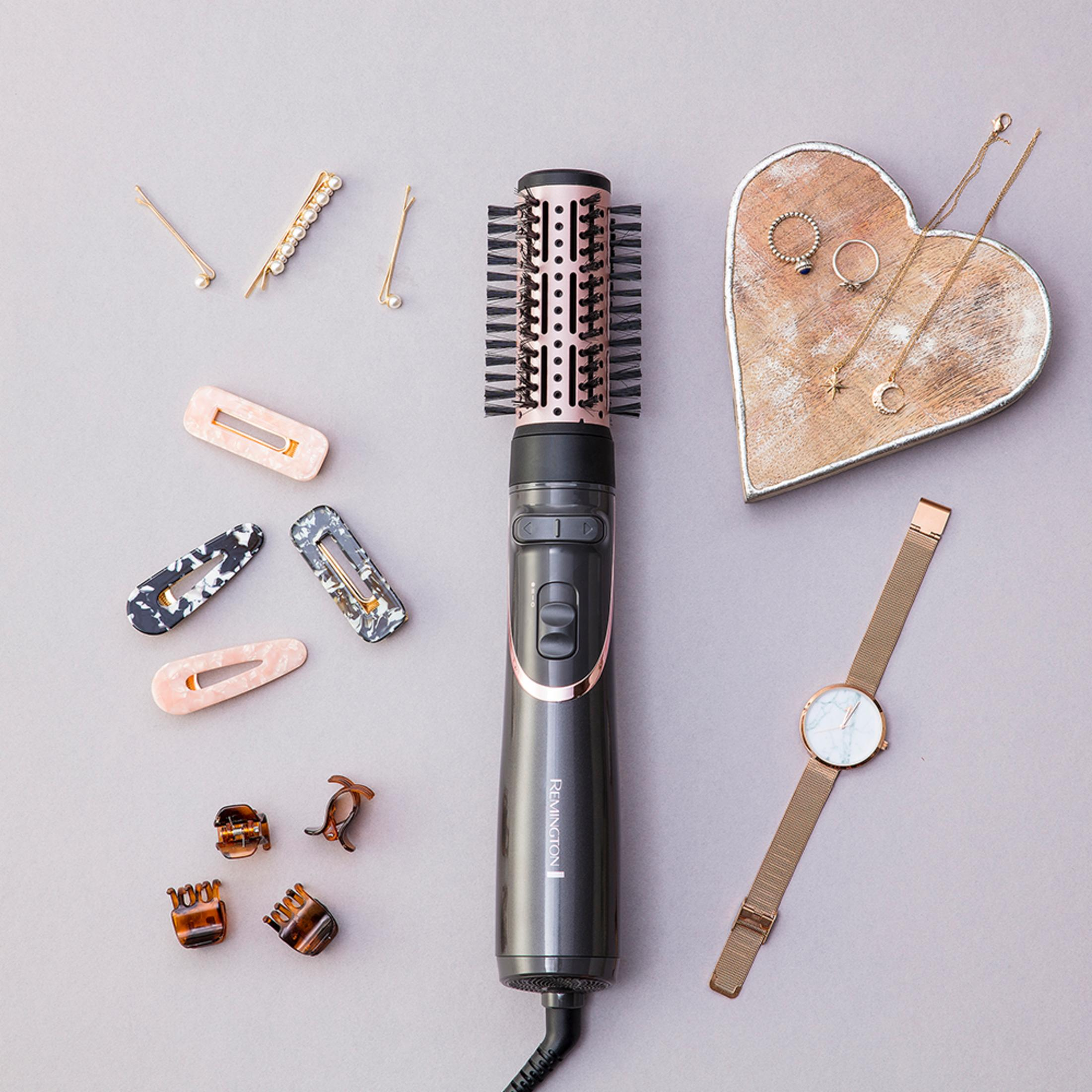 Ciemna lokówka z akcentami w kolorze różowego złota, otoczona spinkami i biżuterią.