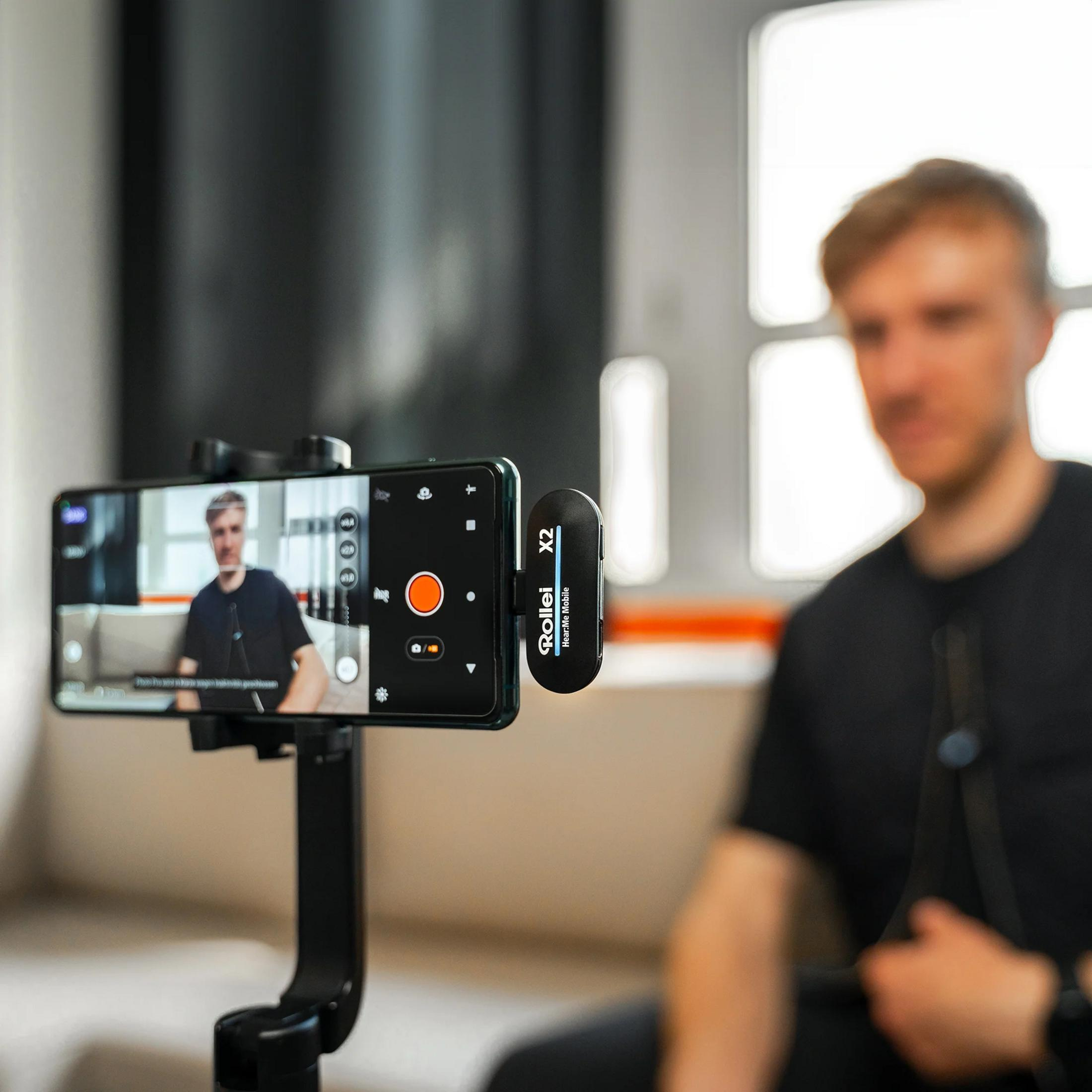 Ein Mann filmt sich mit einem Smartphone auf einem Gimbal, mit Mikrofon.