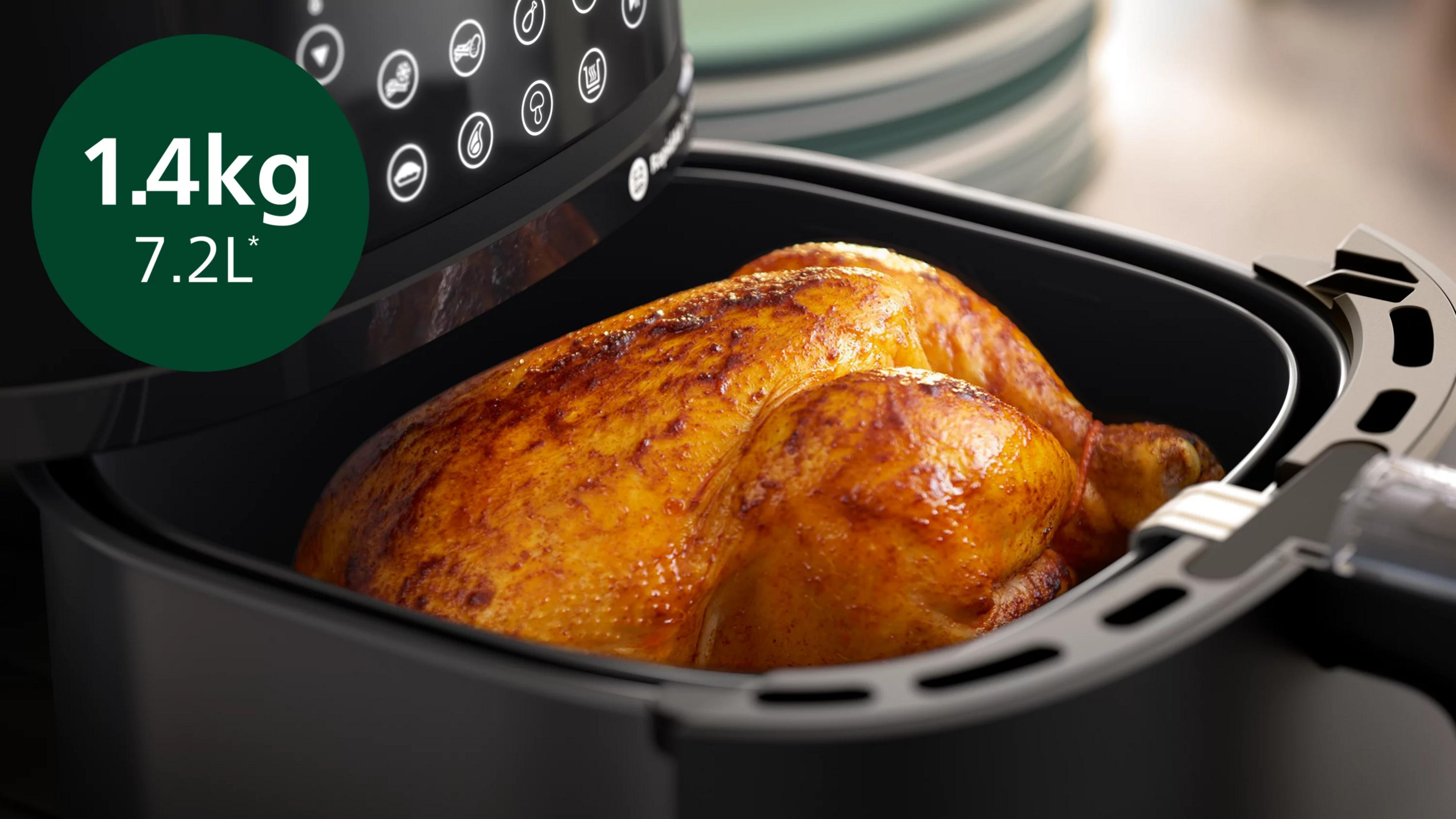 Un poulet rôti doré à l'intérieur d'un panier de friteuse à air noir.