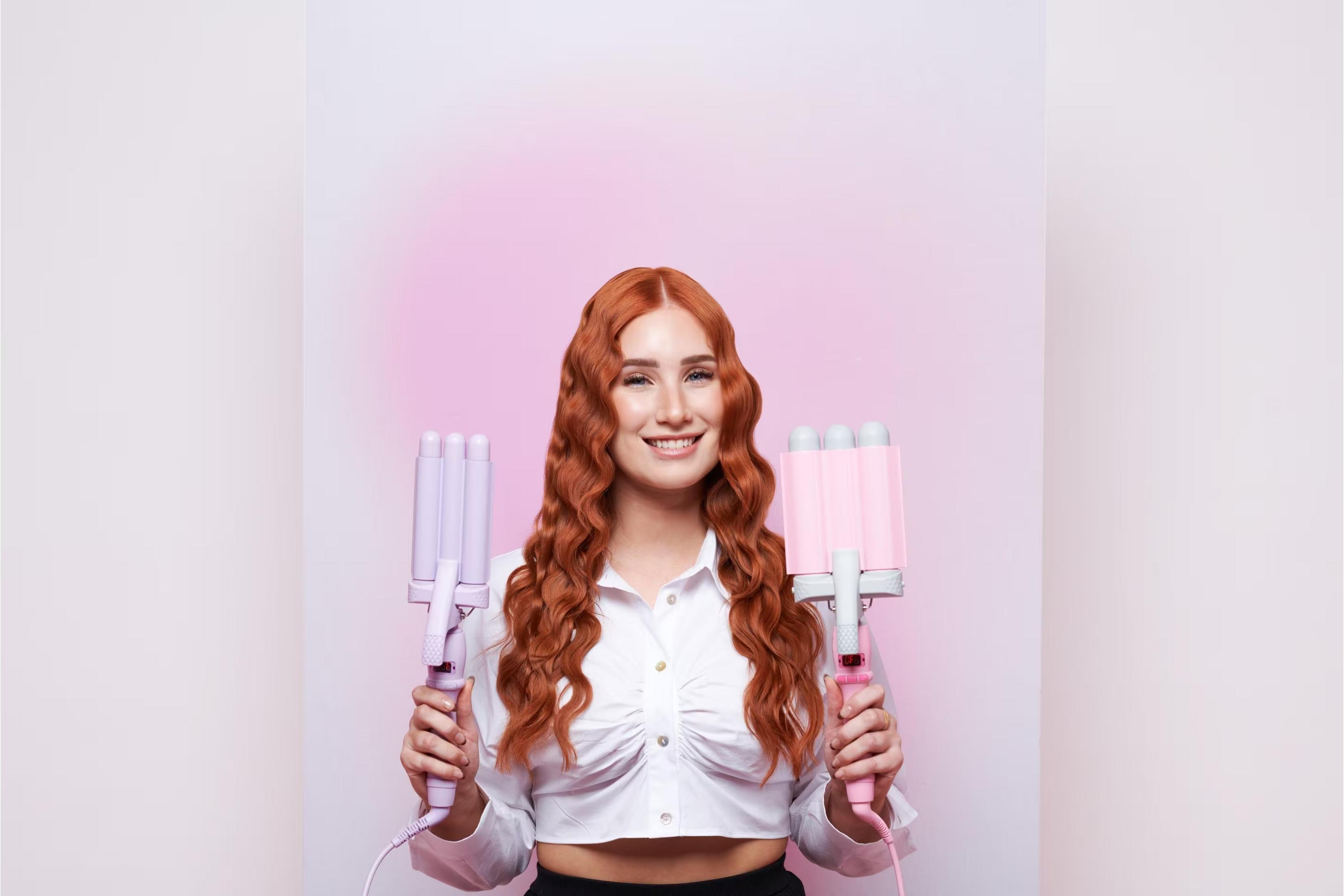 Frau mit roten Haaren hält ein lilafarbenes und ein pinkfarbenes Welleneisen.