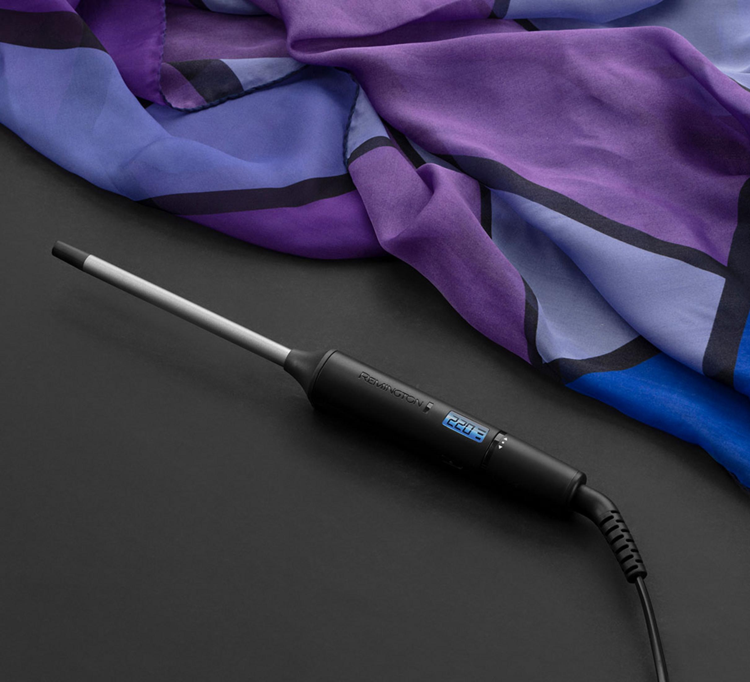 Czarna lokówka Remington z cyfrowym wyświetlaczem leży na fioletowym i niebieskim szalu.