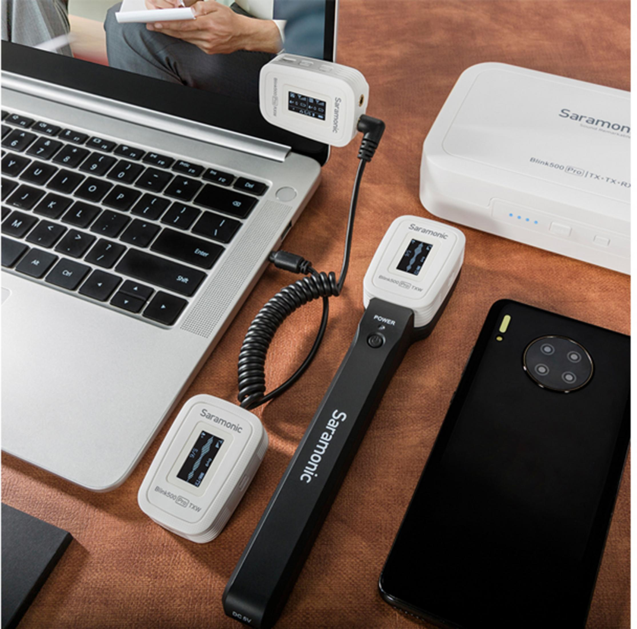 Ein Laptop, ein Smartphone, ein Sender und ein Empfänger auf braunem Untergrund.