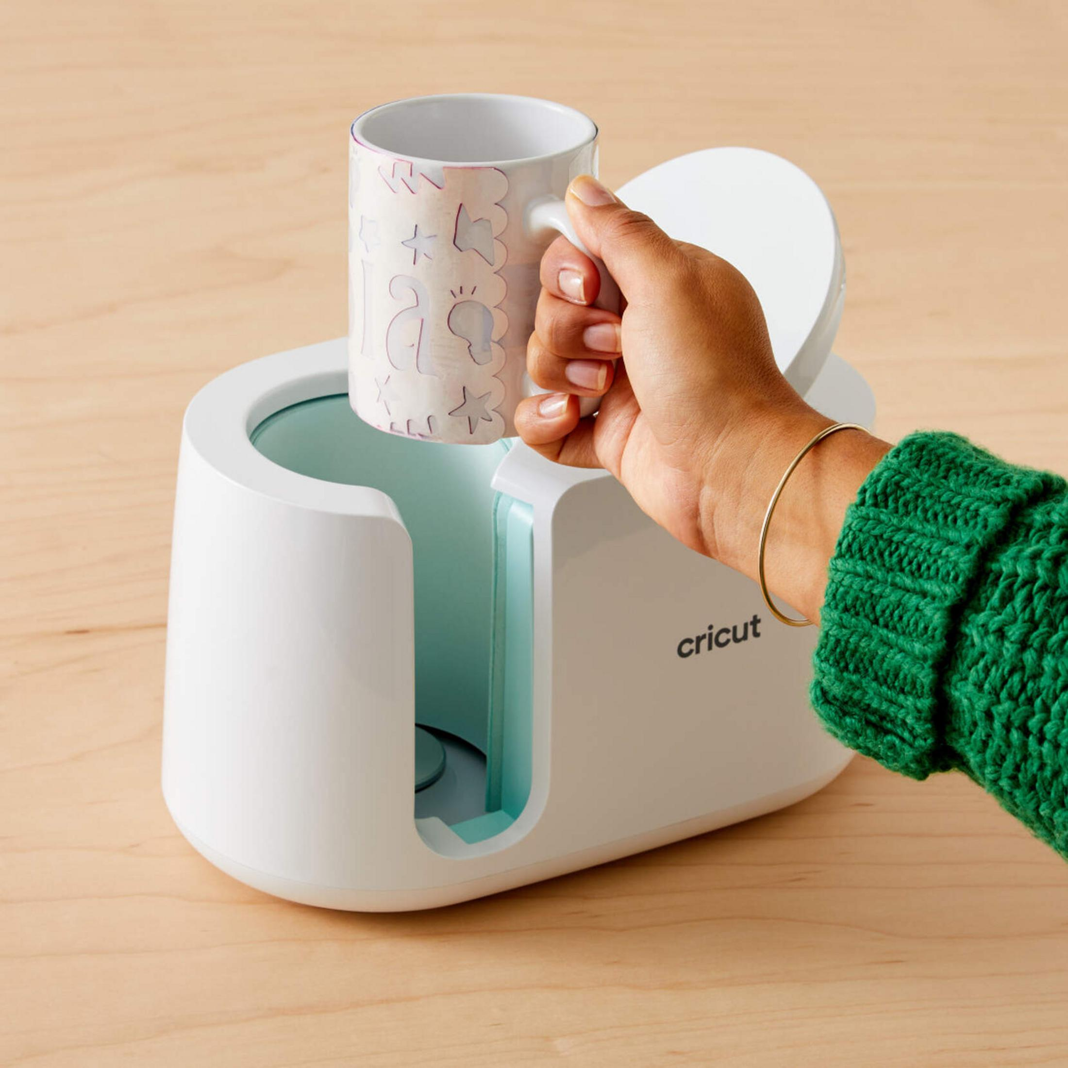 Una mano tiene una tazza in una macchina bianca.