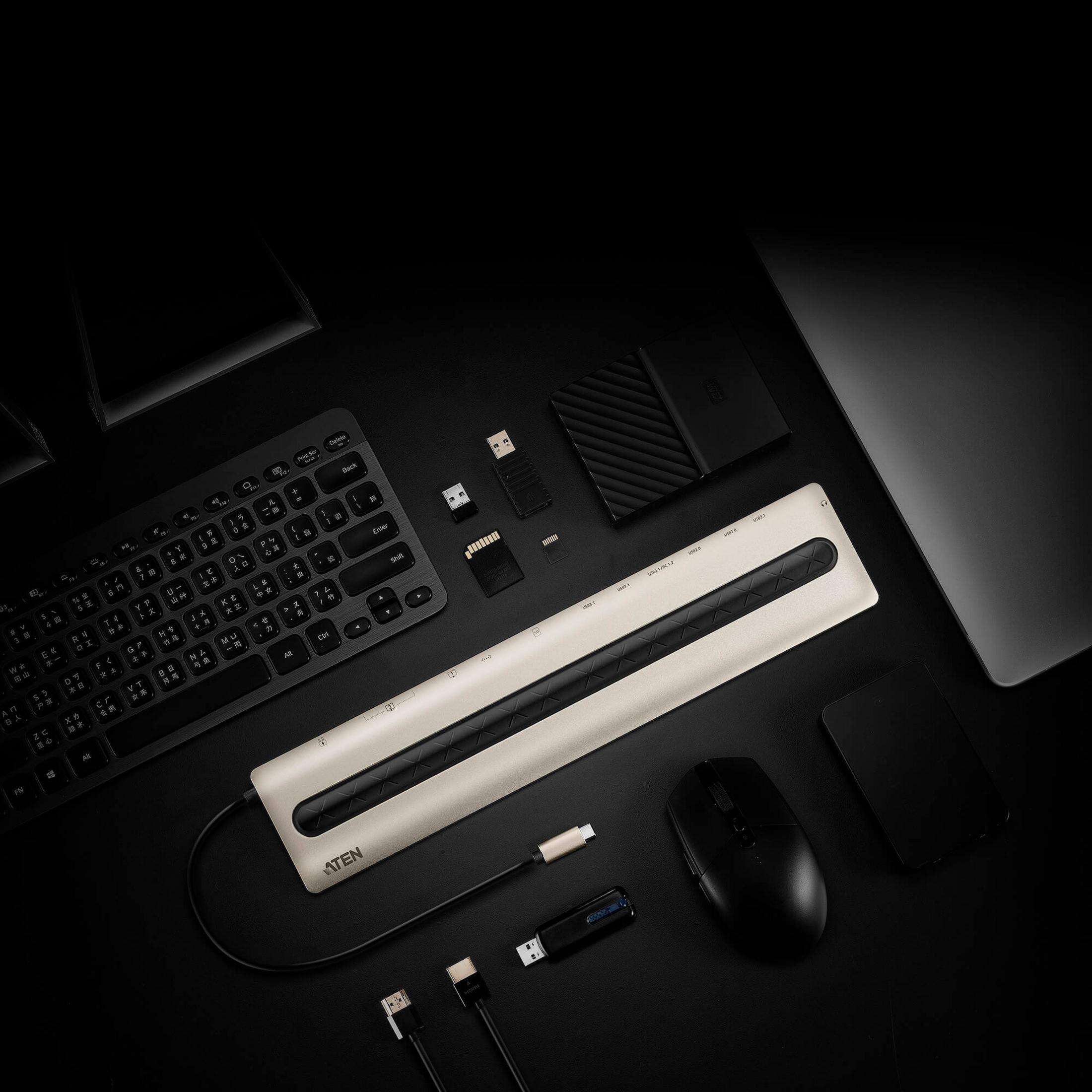Ein Laptop, Tastatur, Maus, USB-Hub, Festplatte, SD-Karte und USB-Sticks auf schwarzem Hintergrund.