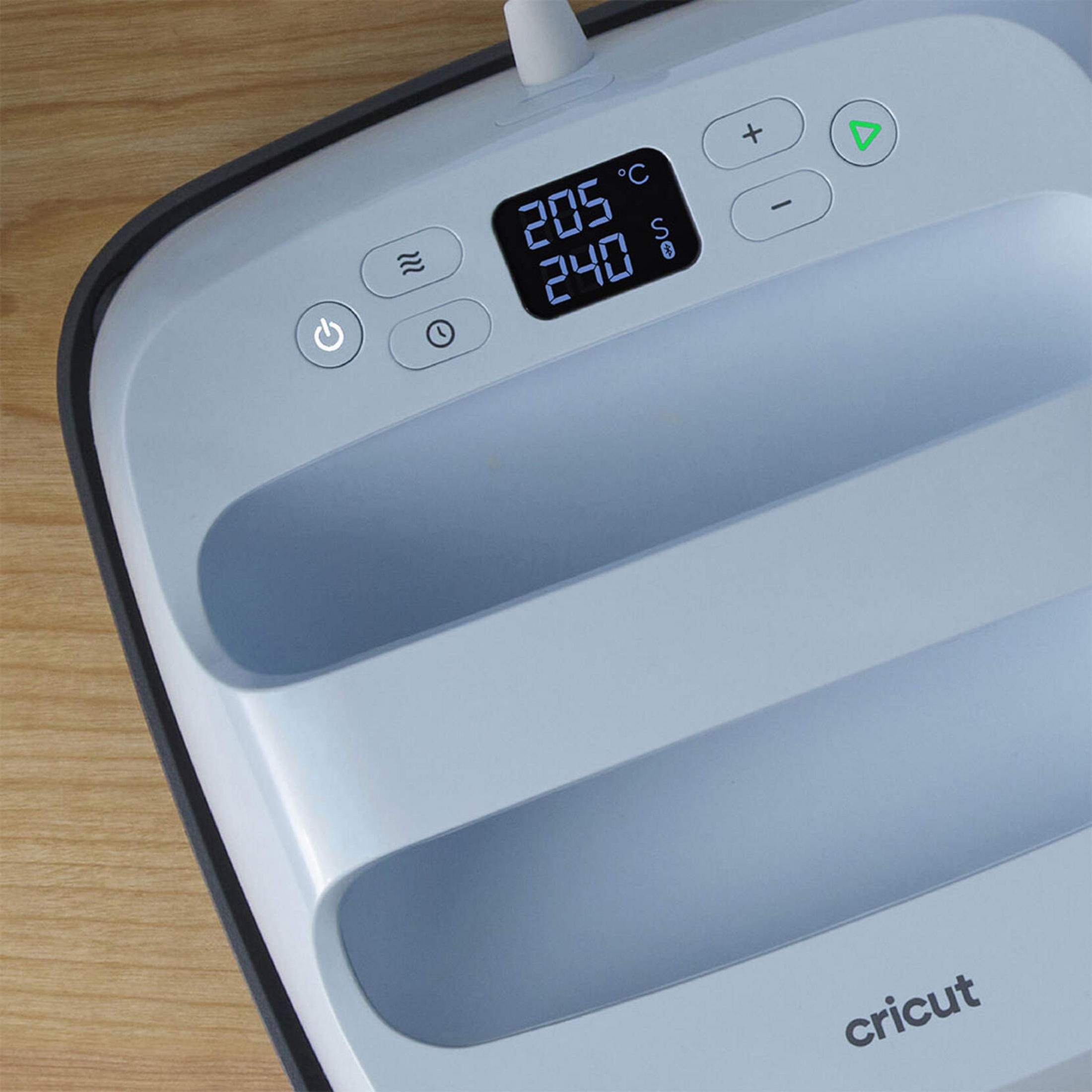 Graue Cricut-Presse mit Digitalanzeige auf Holztisch.