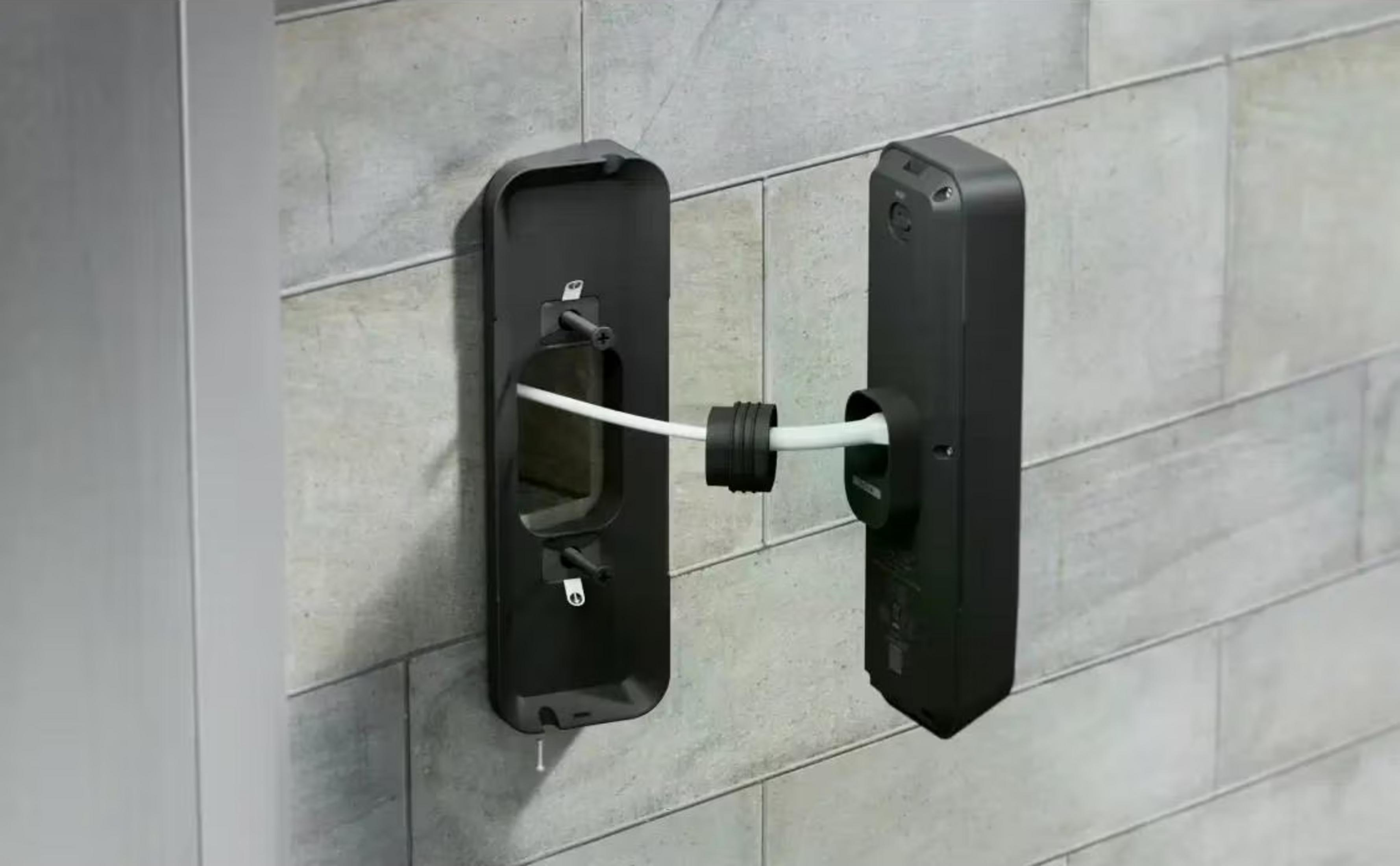 Two black casings and a white cable on a wall.