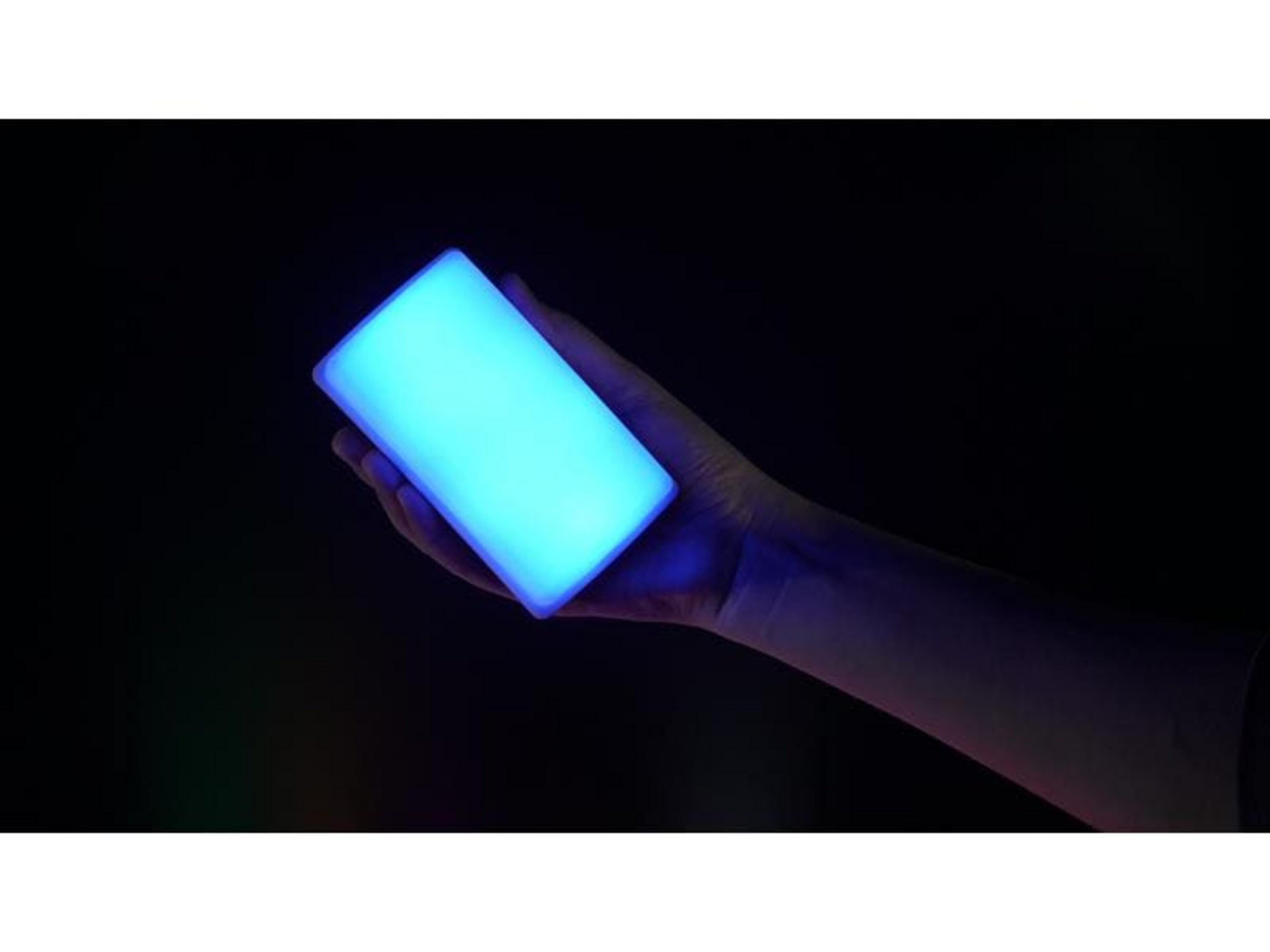 Une main tient une lampe rectangulaire bleue lumineuse.
