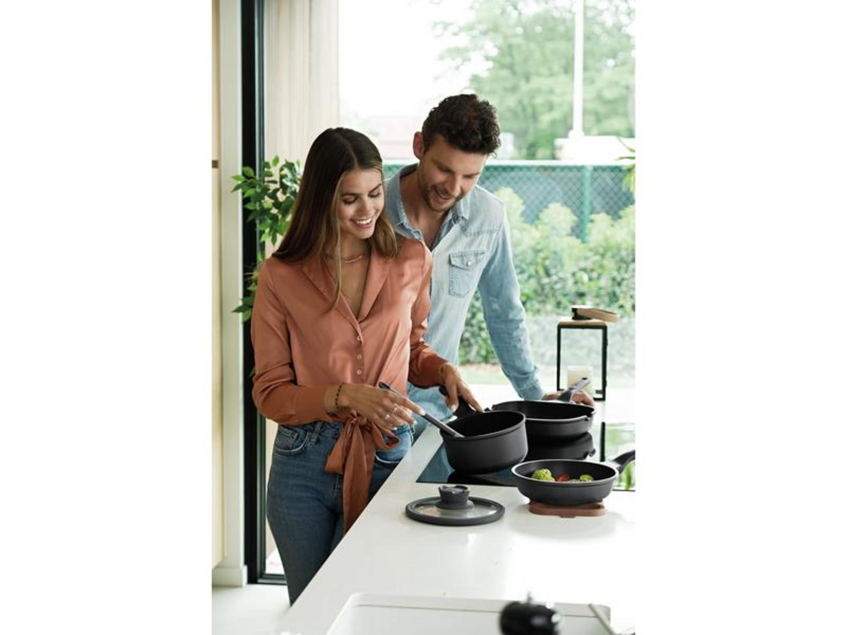 Een man en vrouw koken in een moderne keuken met kookgerei.